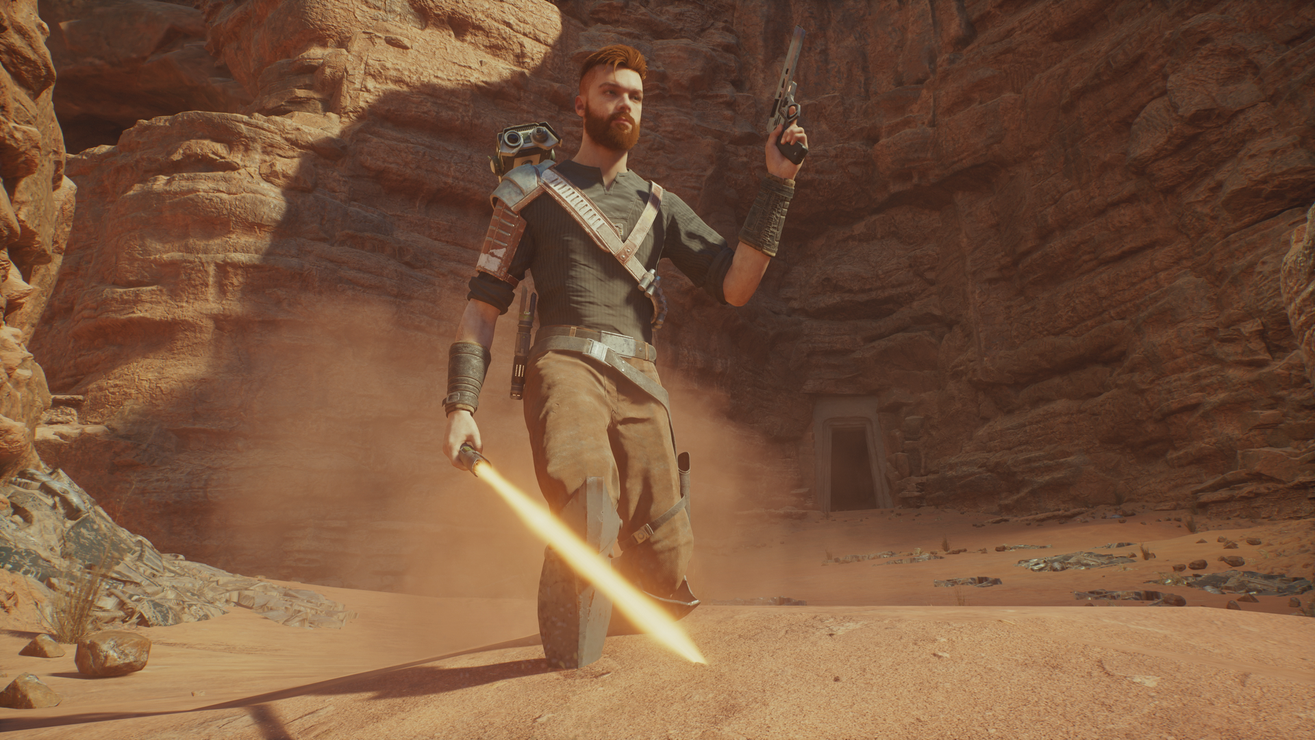 Star Wars Jedi: Survivor Cal Kestis standing in the sand of Jedha brandishing his lightsaber and blaster