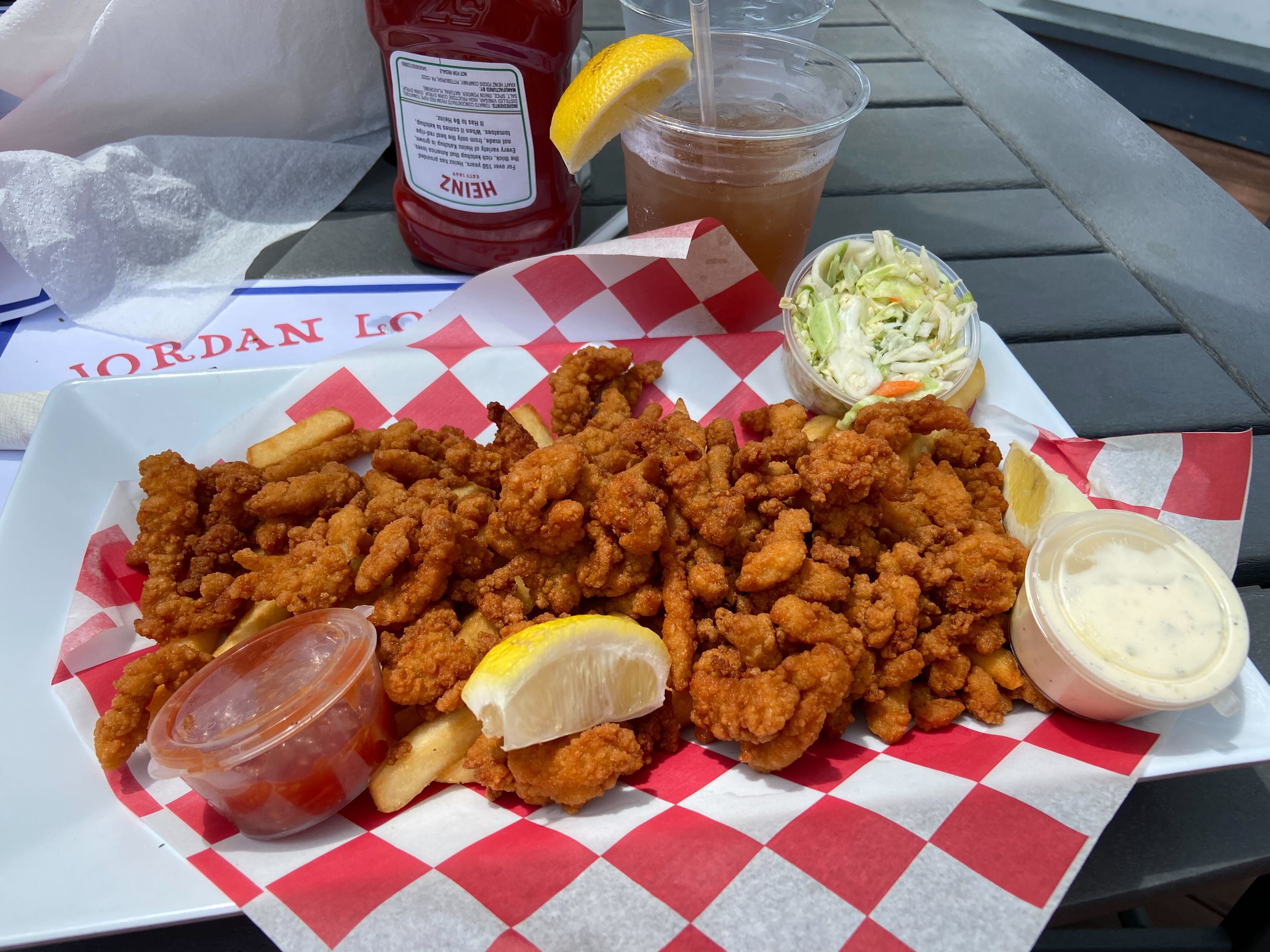 Fried clam strips in a basket with red and white checkerboard paper.