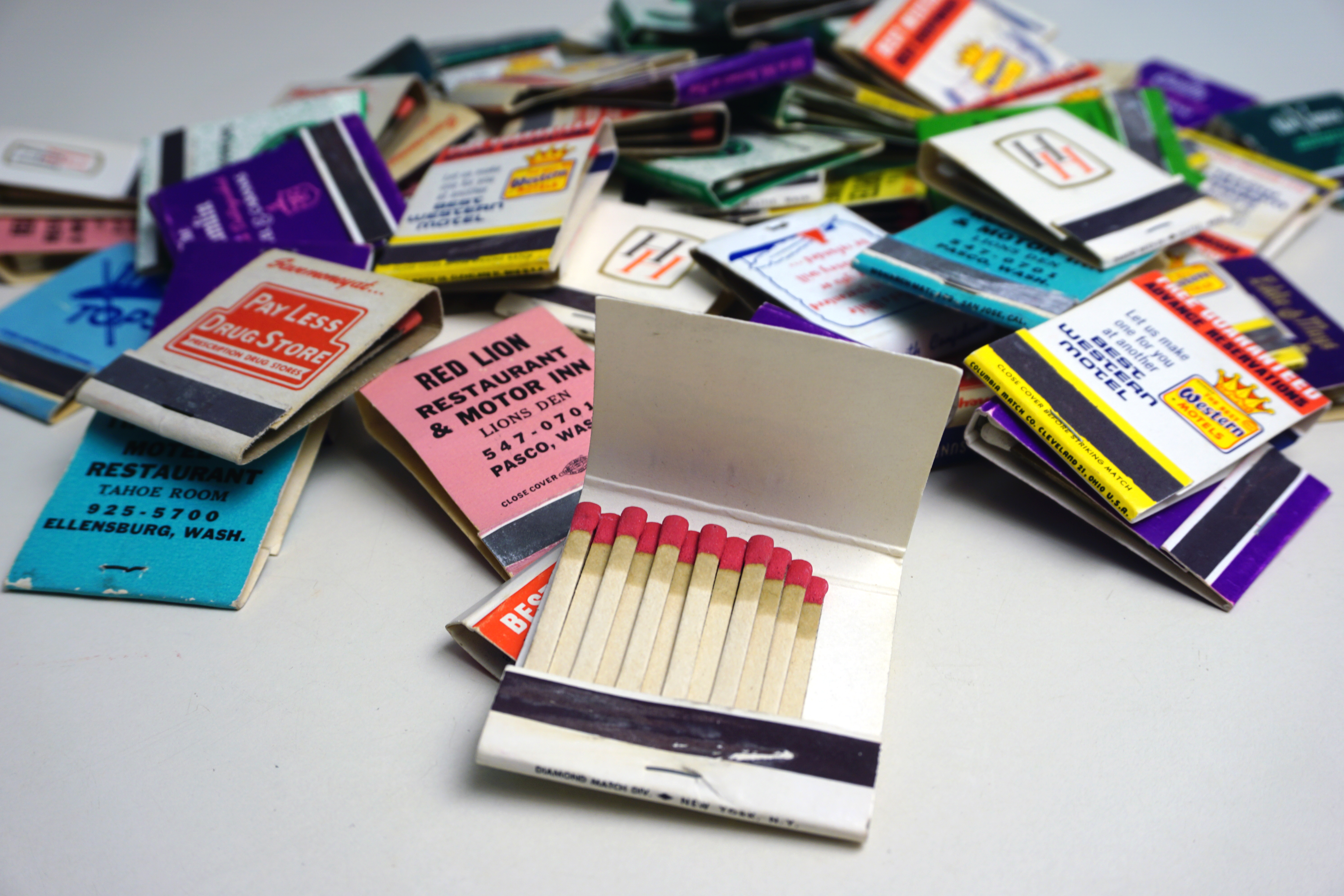 a pile of colorful vintage matchbooks from restaurants, hotels, and other businesses