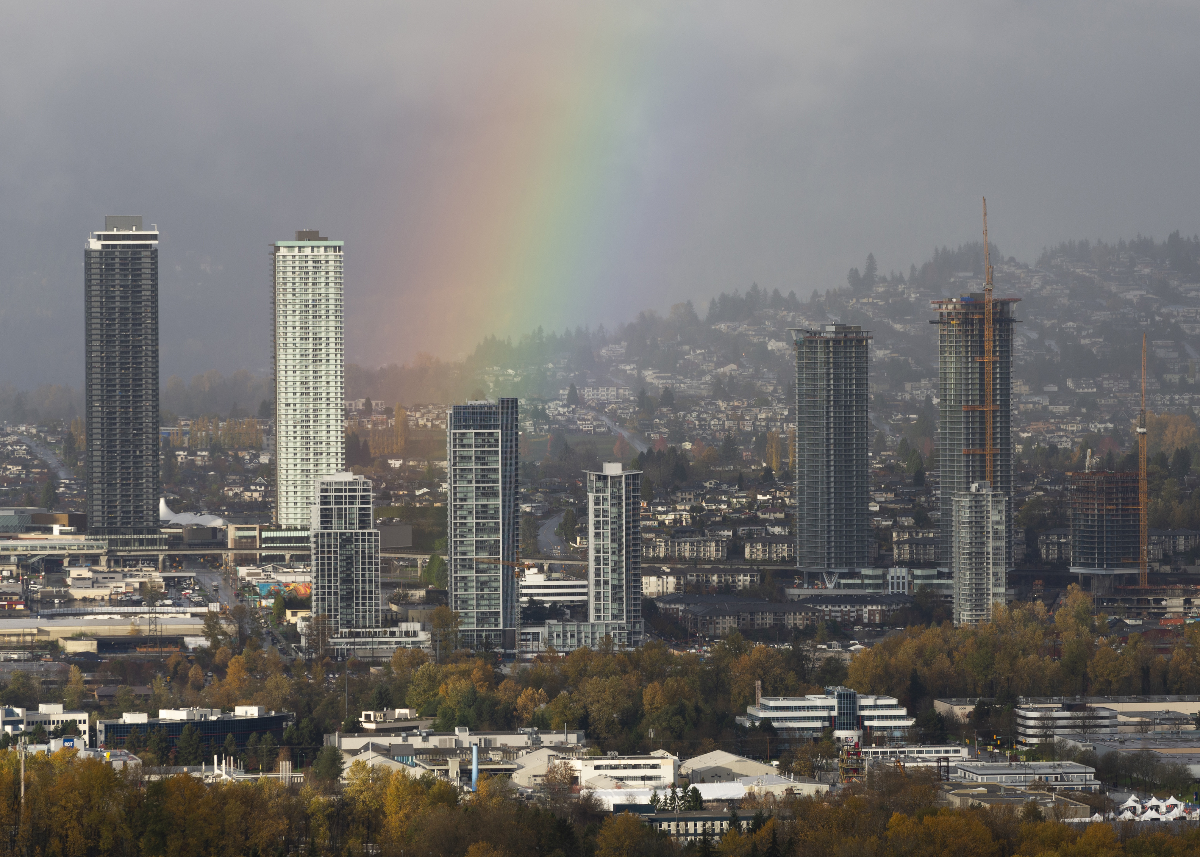 A view of autumn colors on the trees and a rainbow against a view of the metro Vancouver skyline on November 07, 2021 in Burnaby, British Columbia, Canada.