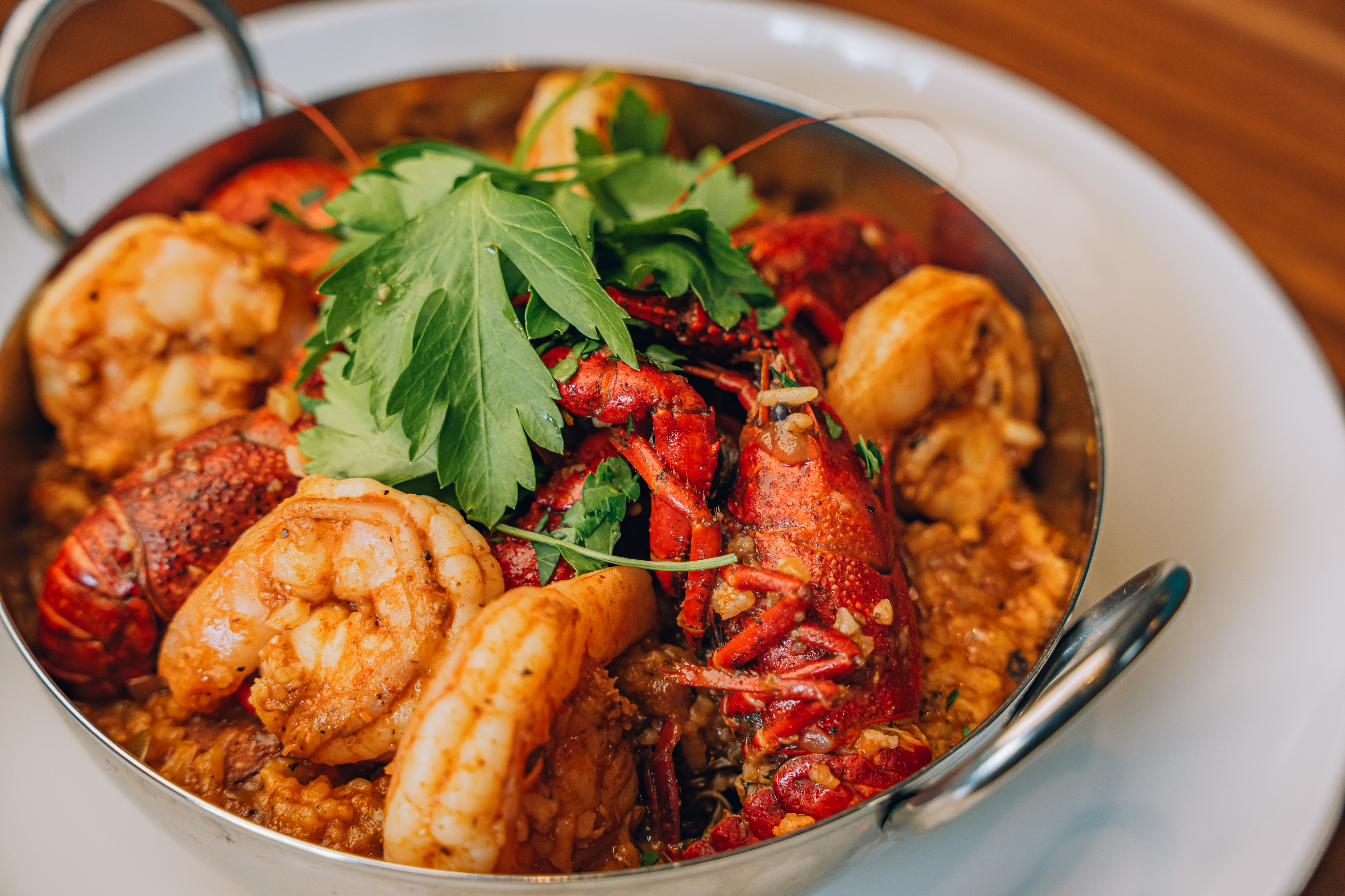 A close-up photo of a bowl of jumbalaya with shrimp, crawfish, peppers, and rice visible.