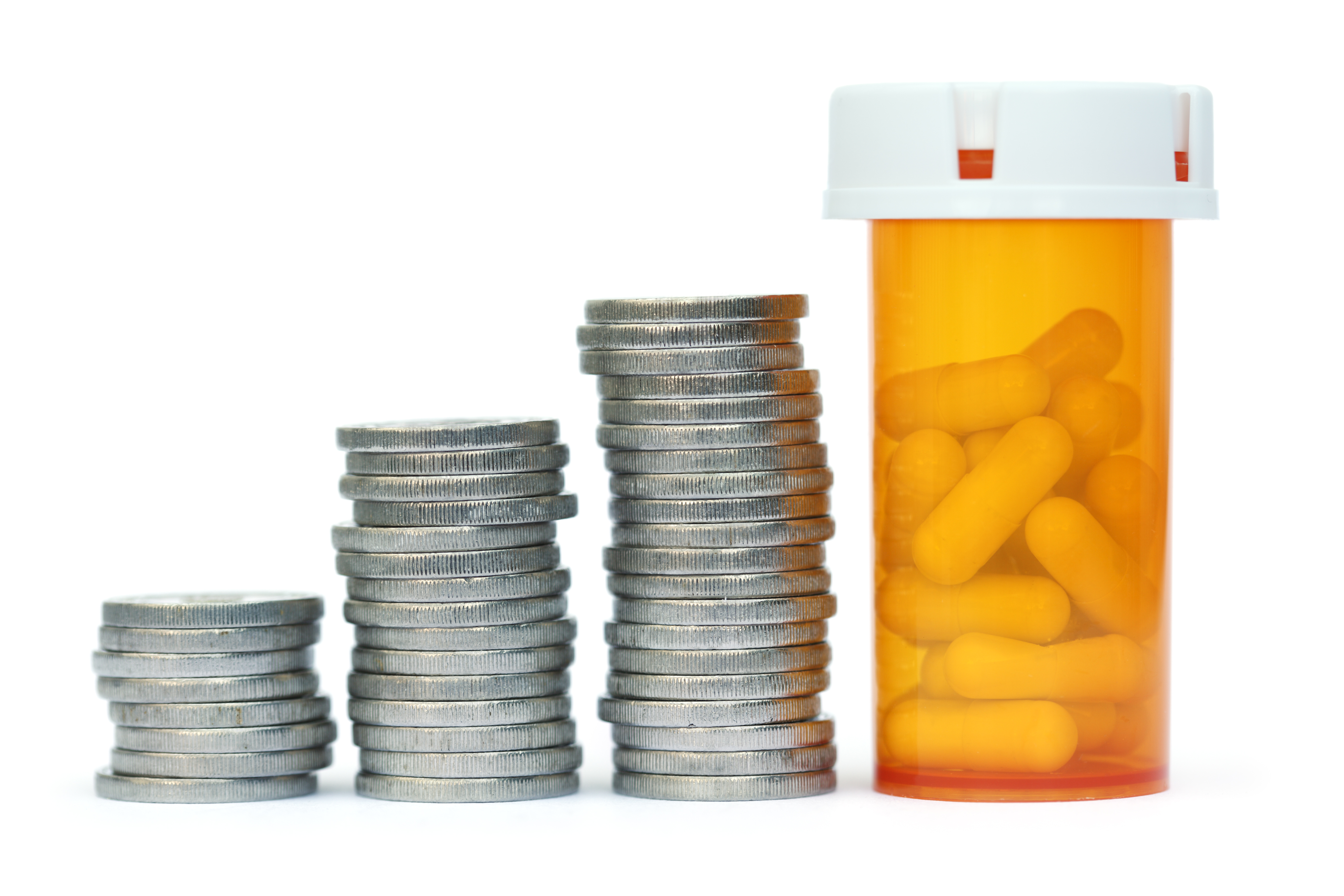 Three stacks of coins in gradually taller amounts from left to right, with a prescription bottle of pills at the right that is tallest.