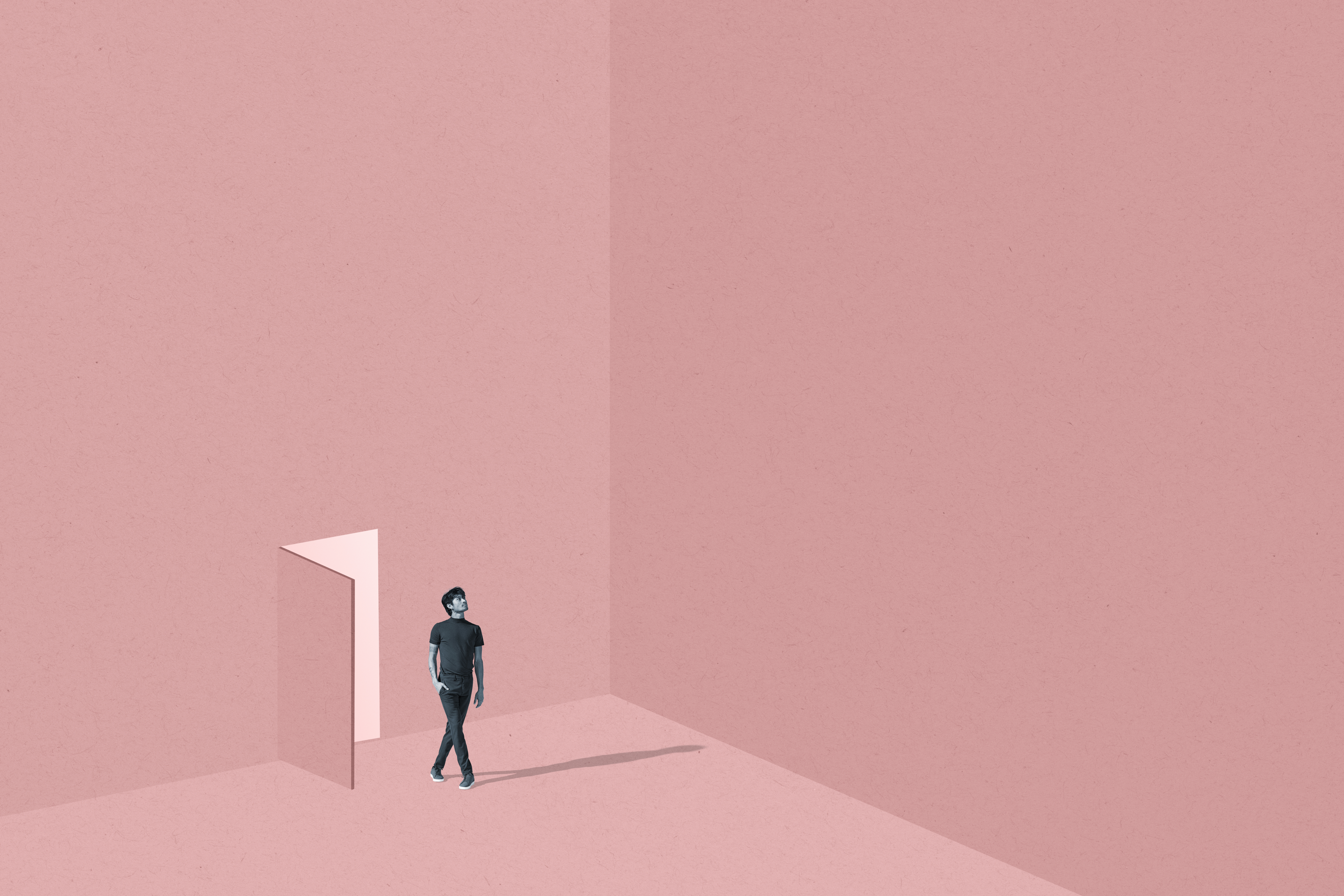 A young person walks through an open door into a spacious, blank, pink room. 