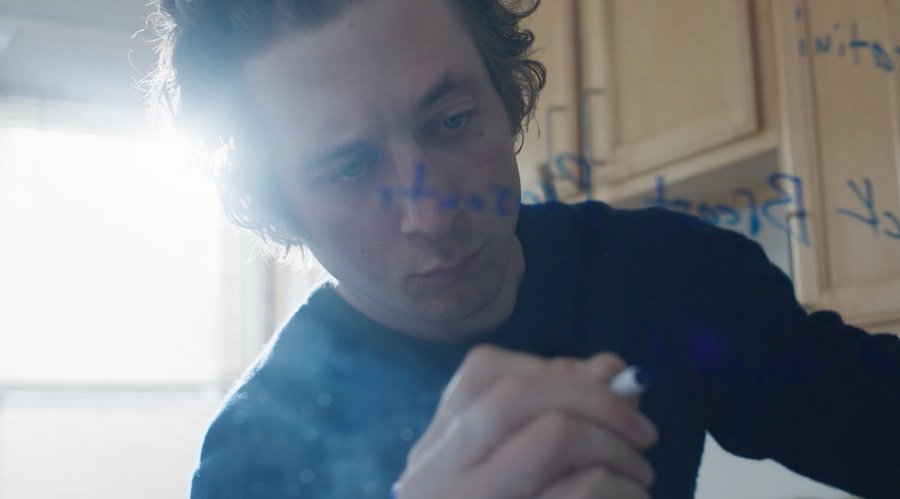 Jeremy Allan White as Carmy, writing on a whiteboard with a blue marker.
