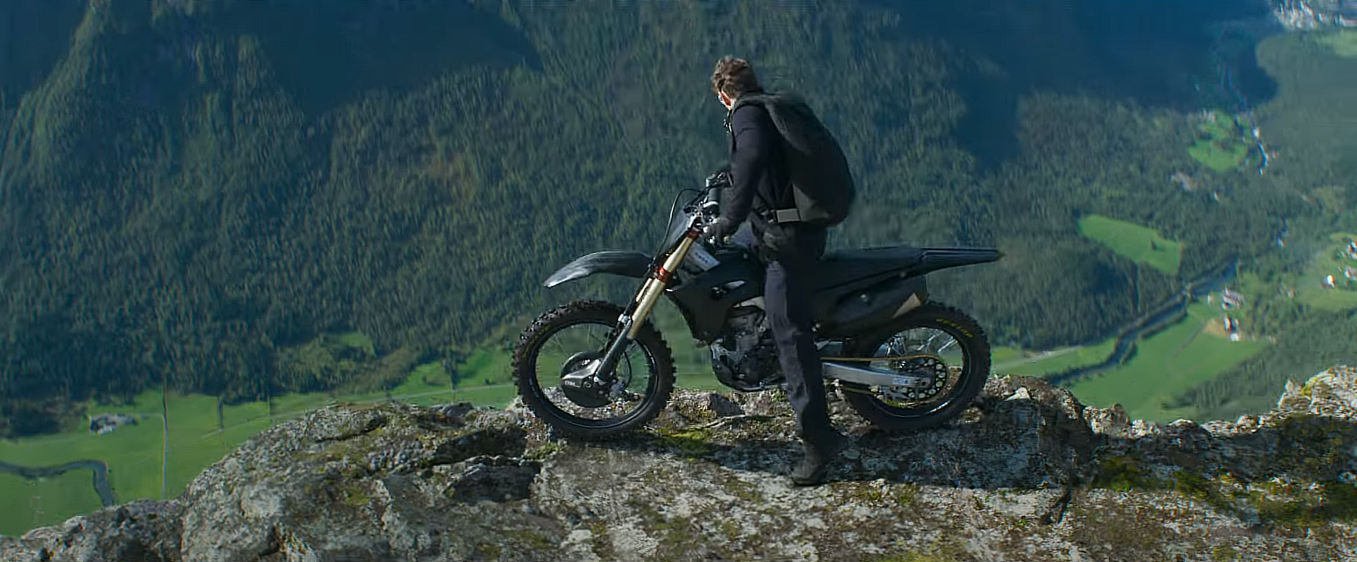 Tom Cruise on a motorcycle at the edge of a cliff in Mission Impossible — Dead Reckoning Part 1 