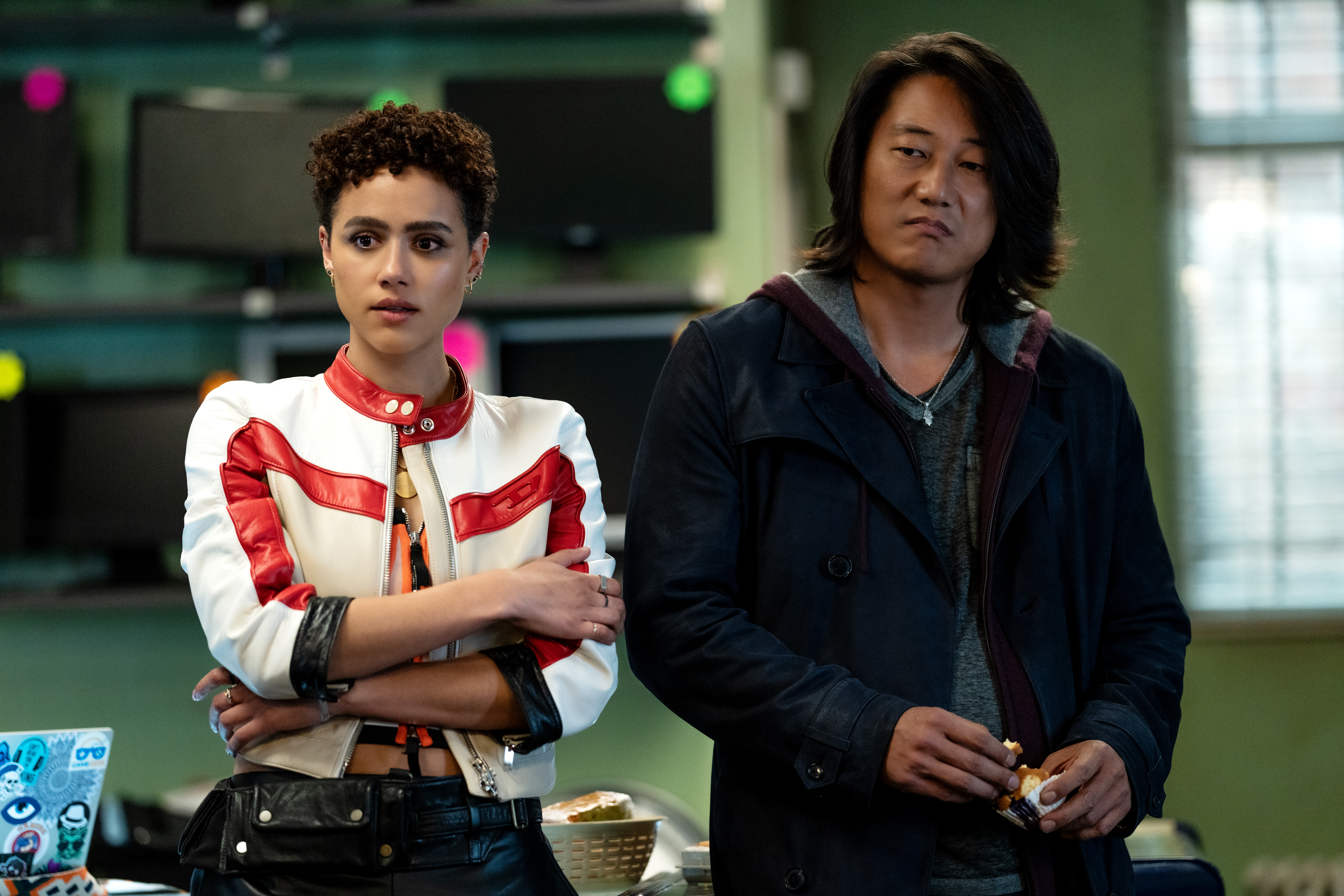 Ramsey (Nathalie Emmanuel) and Han (Sung Kang) stand and listen to yet another plan from their Fast family in Fast X