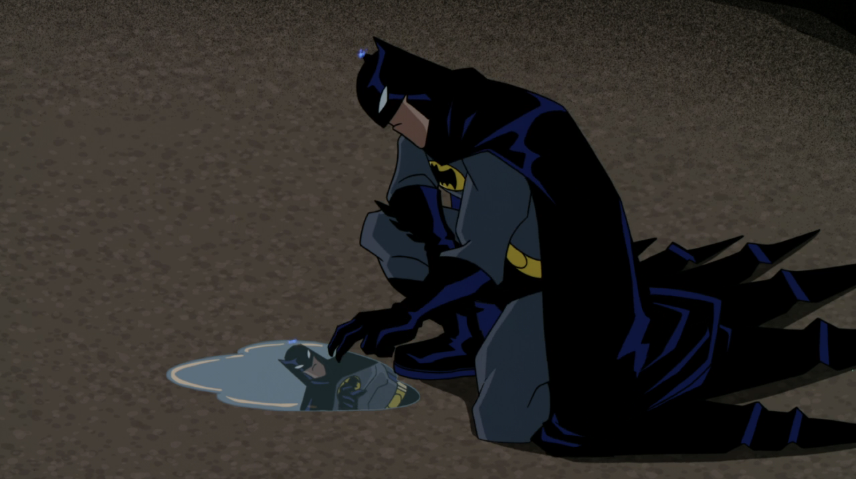Batman looking at himself in a puddle on the ground