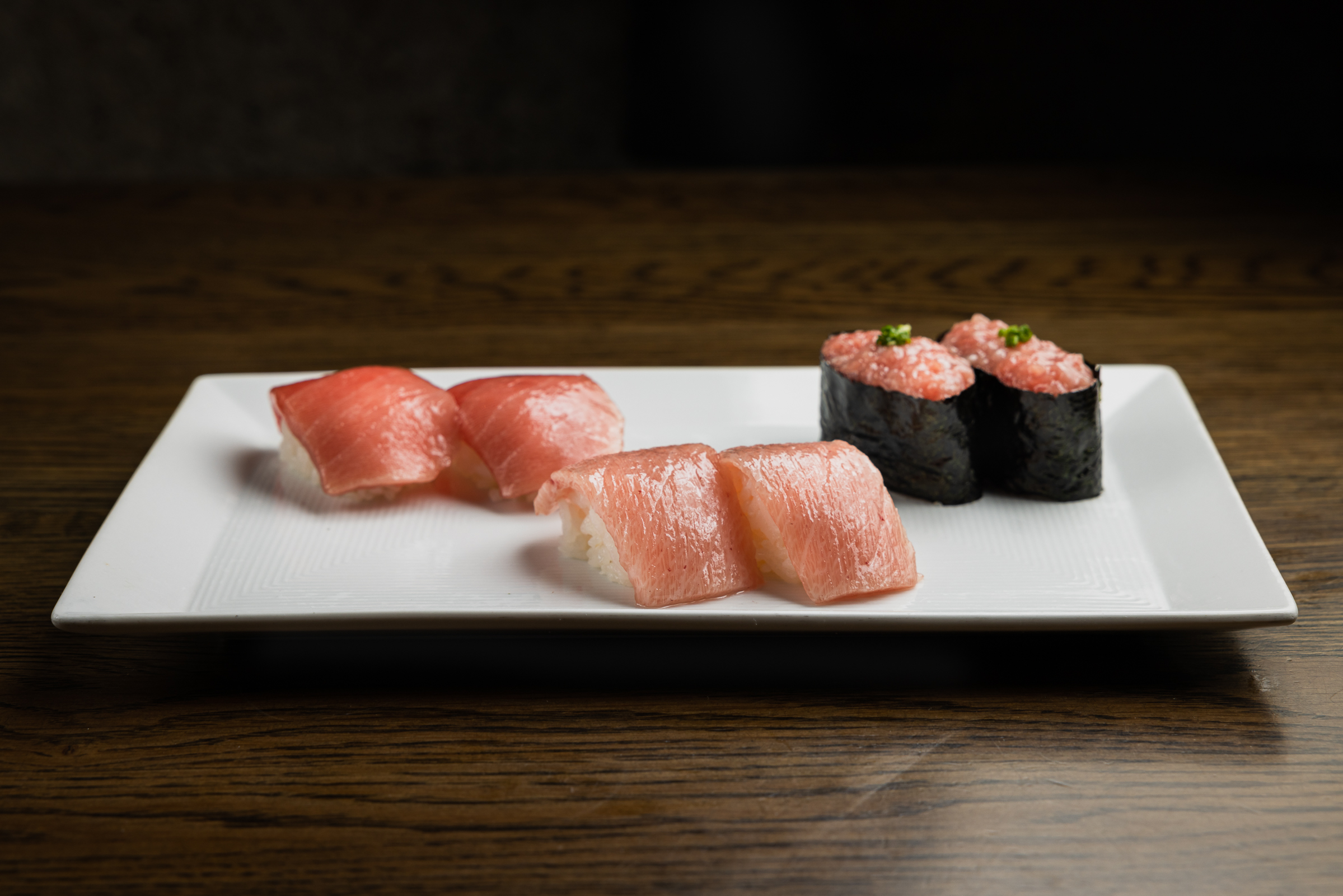 A white plate with nigiri and sushi in dramatic lighting.