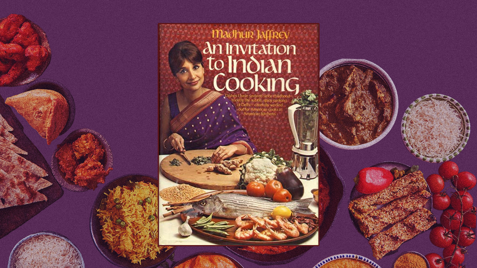 The cover of the 1973 edition of An Invitation to Indian Cooking: Madhur Jaffrey, wearing a purple sari, stands behind a table full of ingredients.