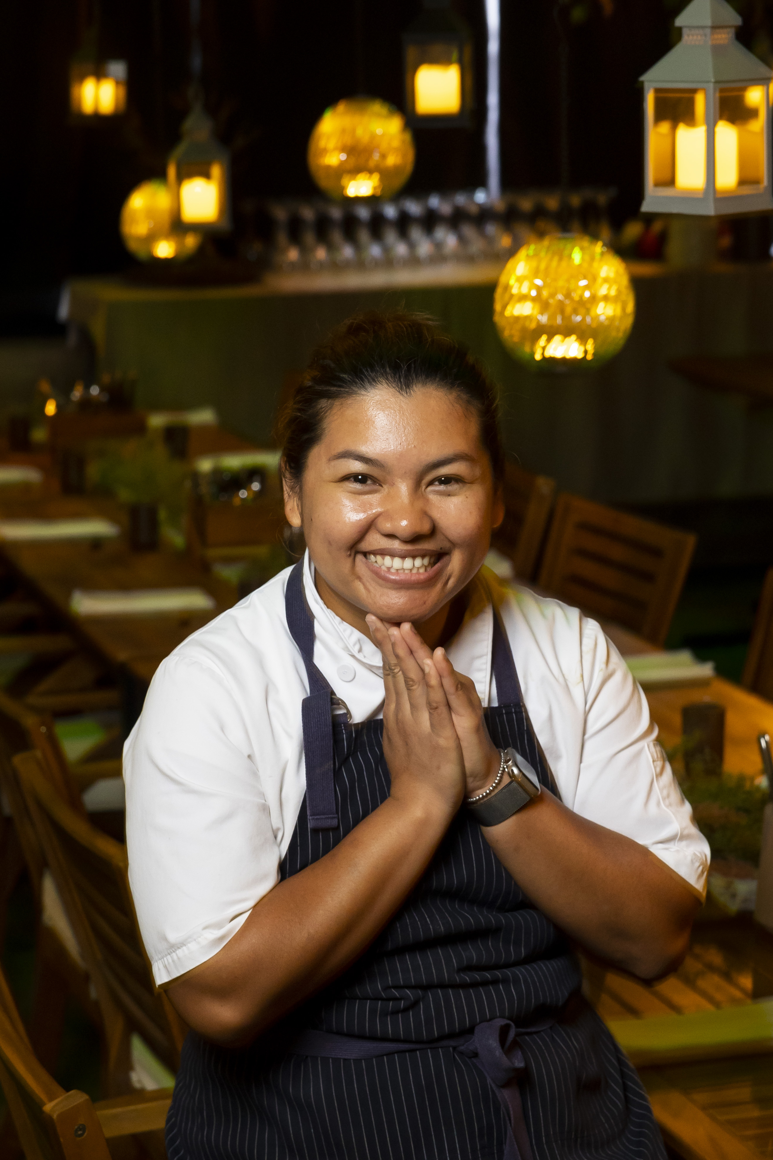 Chef Benchawan Jabthong Painter smiles and sits were her hands folded in the dining room of Th Prsrv.
