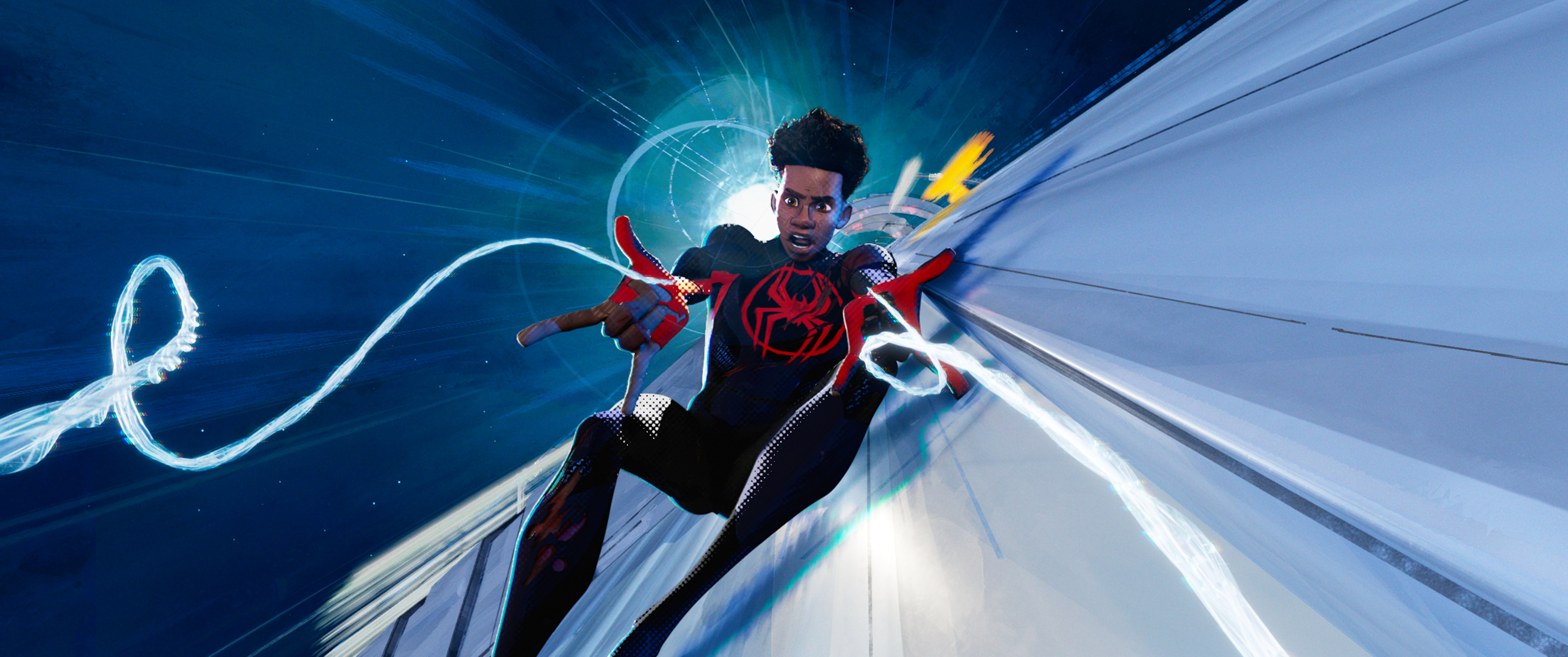 Miles Morales in his suit, without his mask, falling down a sleek white building and using his web shooters to catch onto something. 