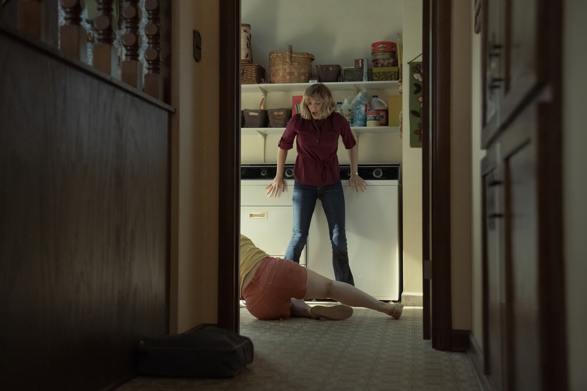 Candy (Elizabeth Olson) looks startled at Betty (Lily Rabe) on the ground, as shot through a doorway, in a still from Love &amp; Death on HBO