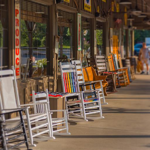Rainbow-painted rocking chairs outside of a Cracker Barrel.