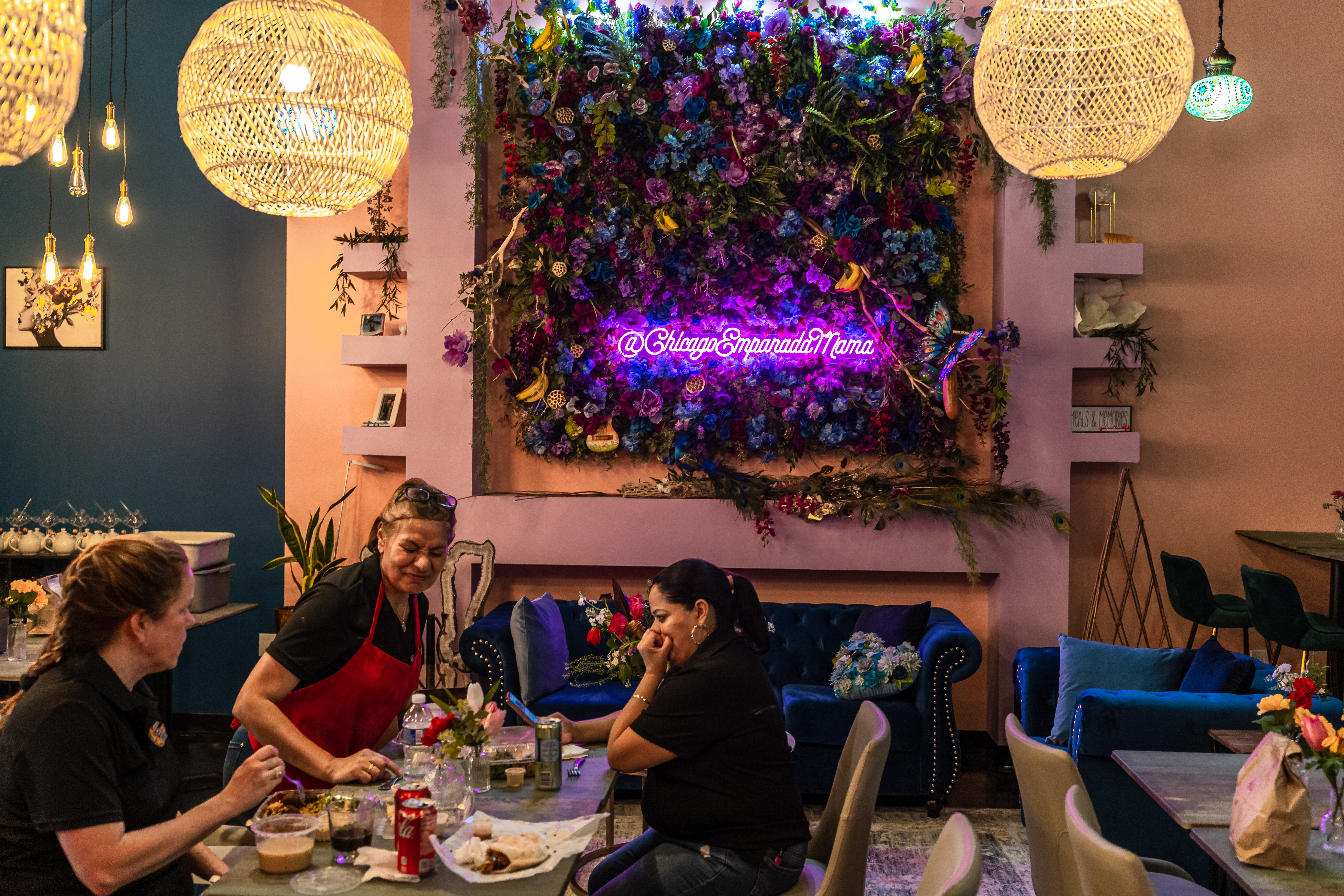 A section of a restaurant space is decorated with a purple neon sign that reads “@ChicagoEmpanadaMama.”