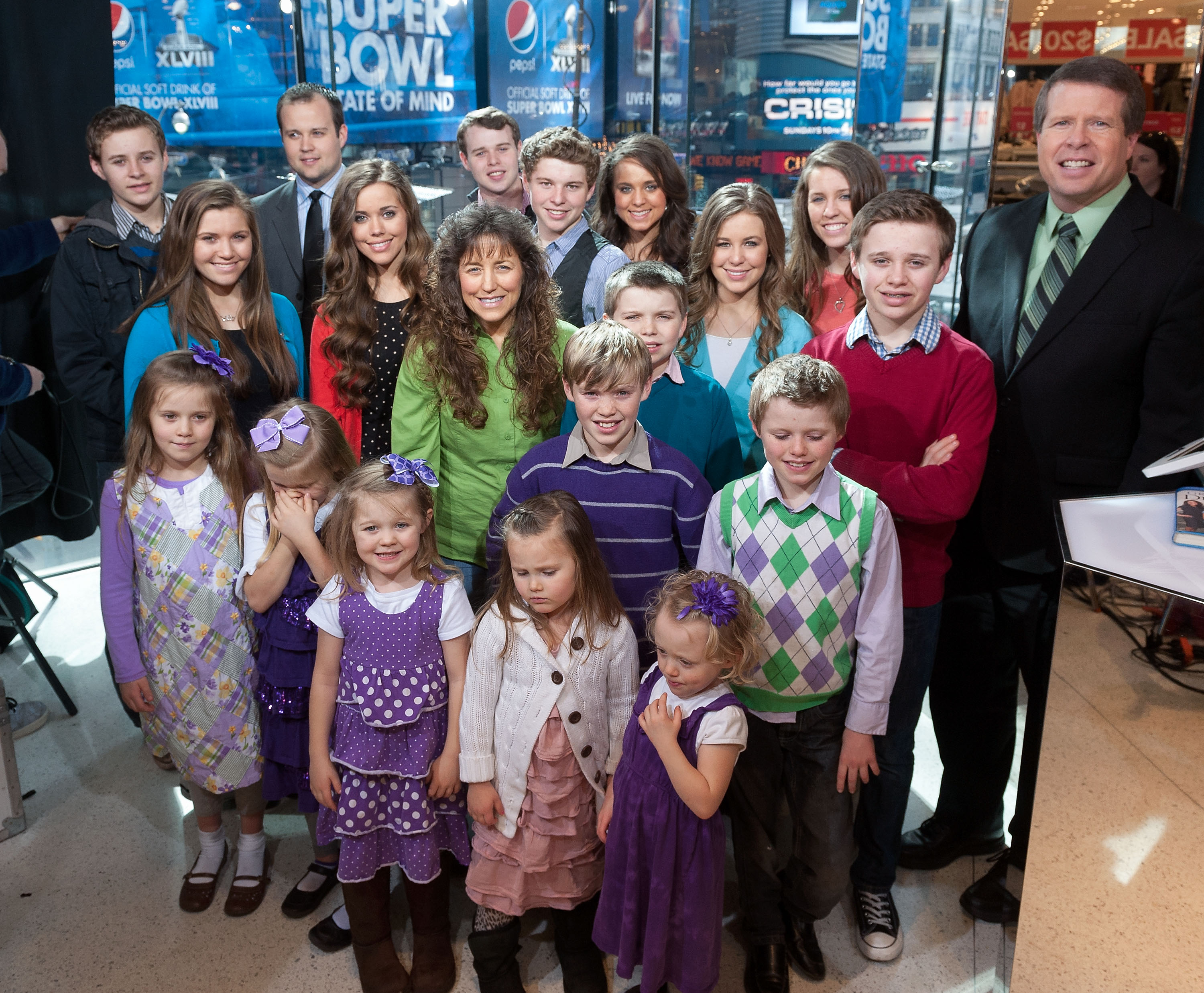 A family with many children, standing on a TV talk show stage.