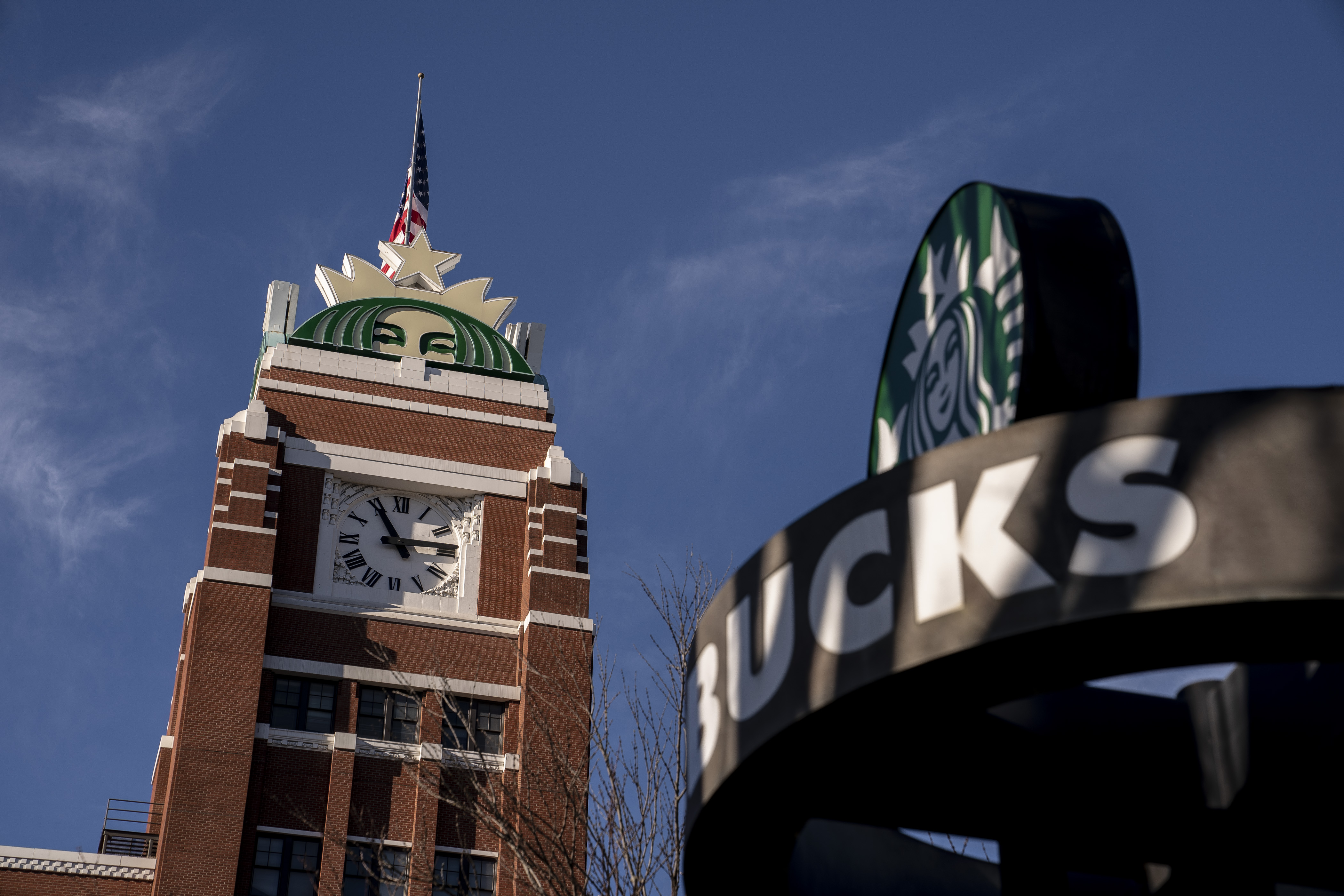 The top of a clocktower with Starbucks iconography; closer, there is a Starbucks sign