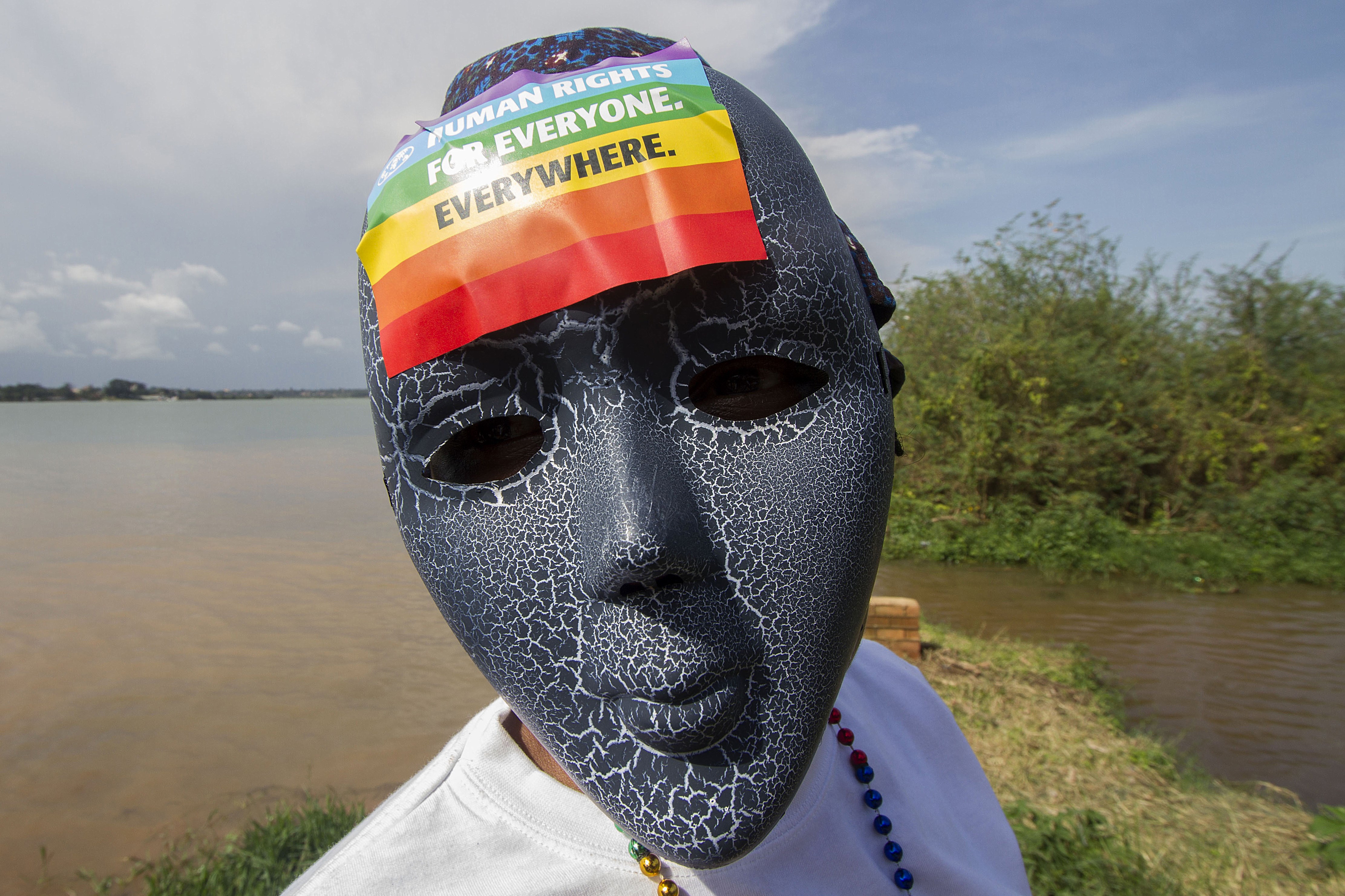 A person in a mask with a rainbow sticker on the forehead. 