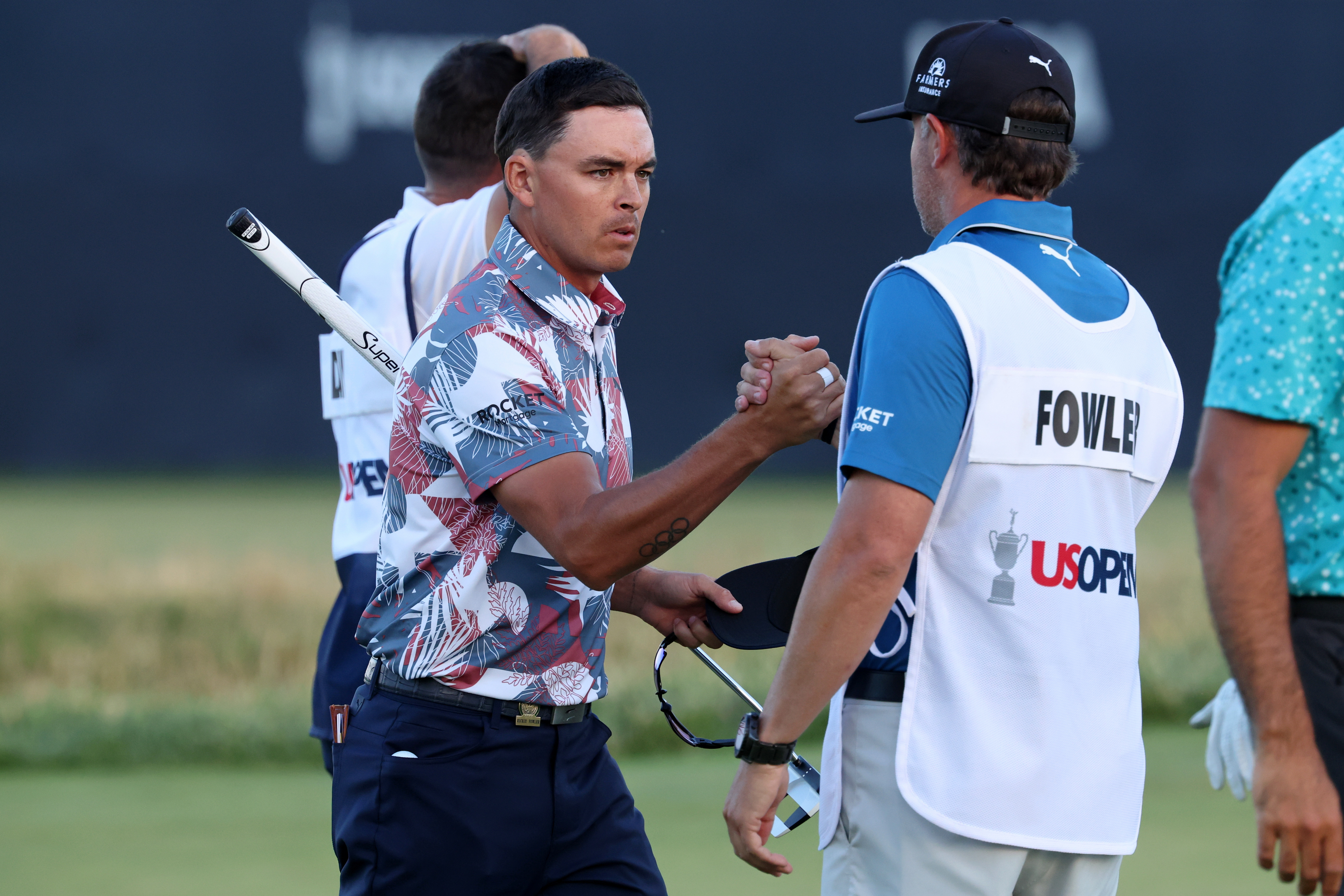Rickie Fowler and his caddie Ricky Romano shake hands on the 18th green after completing the second round of the U.S. Open golf tournament at Los Angeles Country Club.