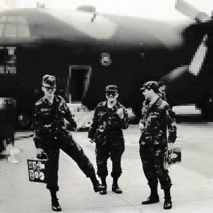 a black-and-white photo of three soldiers standing in front of a military plane