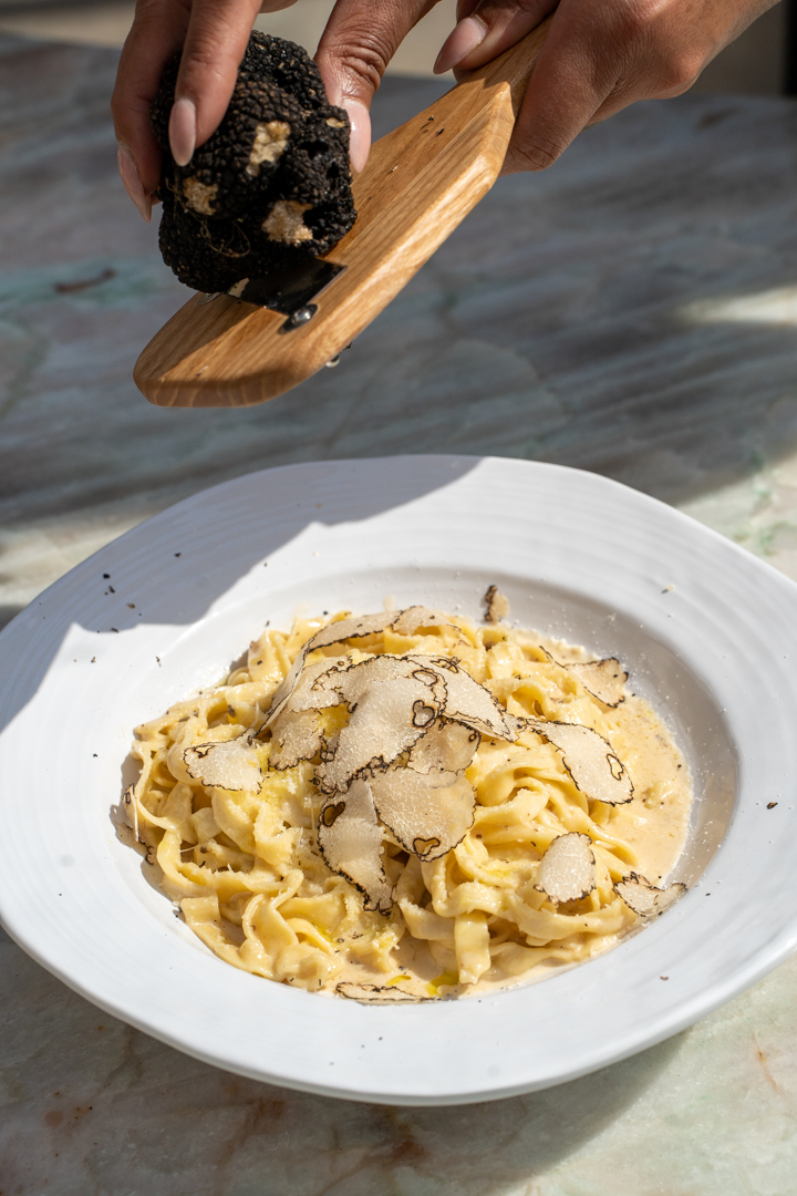 Truffles shaved onto golden pasta on a white plate