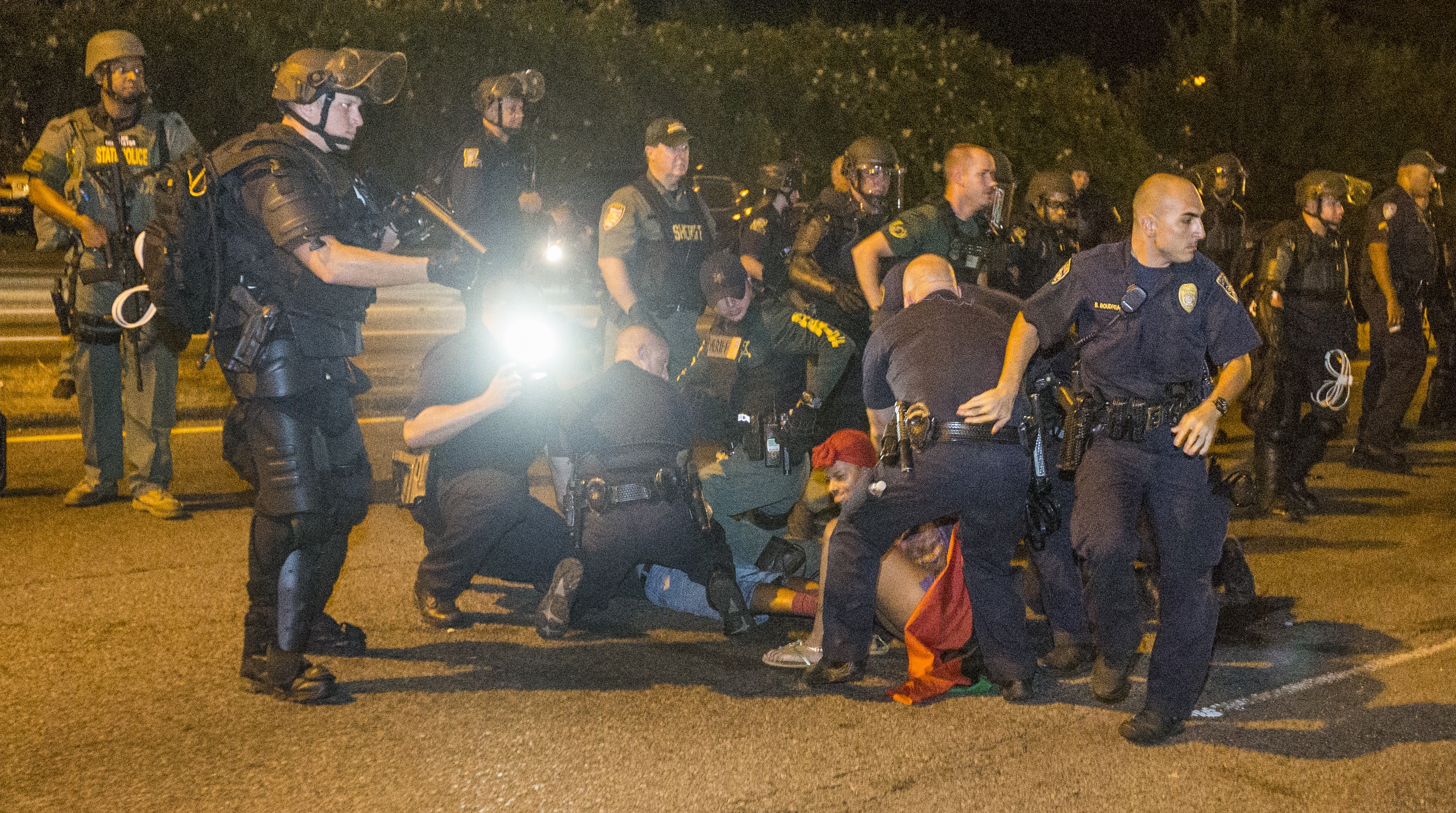 A photo shows police arresting protesters. 