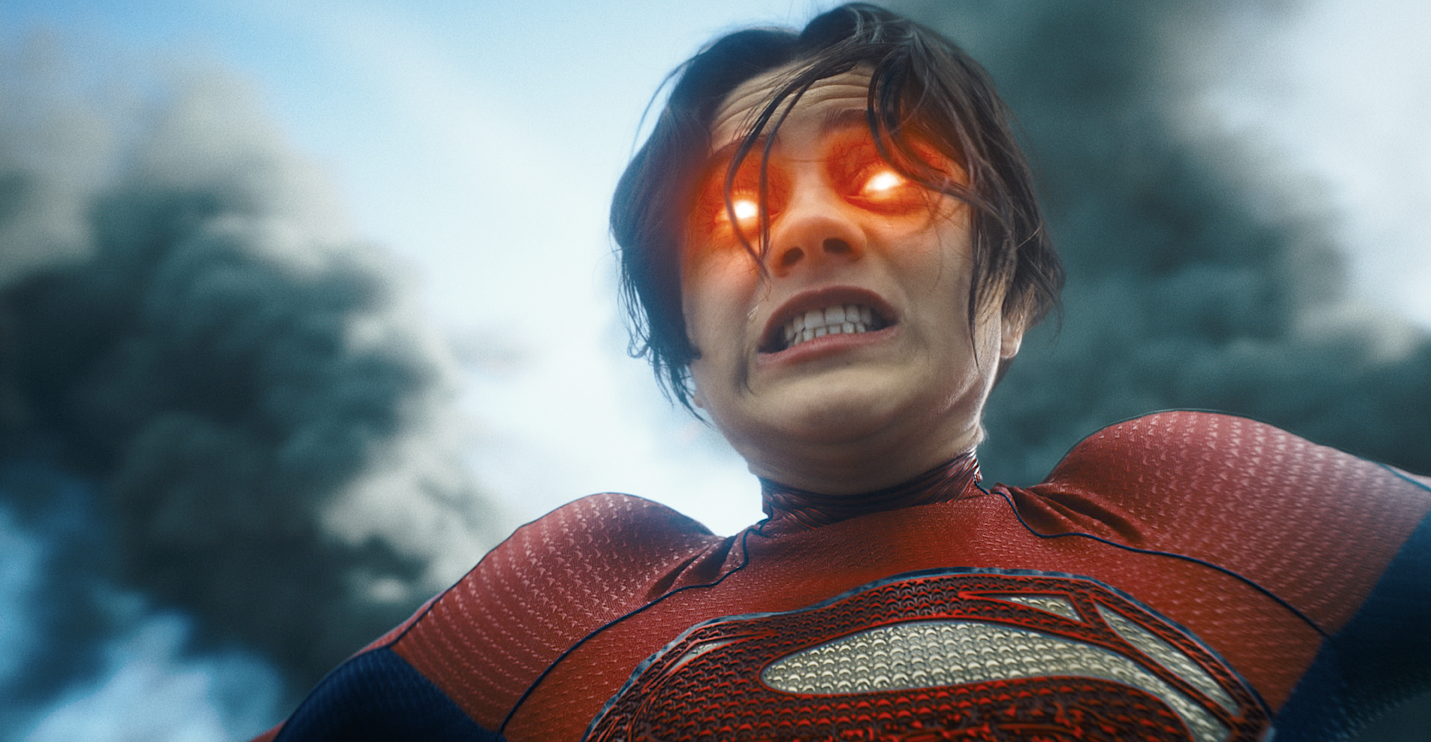 Sasha Calle as Supergirl in the 2023 movie The Flash grits and bares her teeth as her eyes light up red and she prepares to shoot heat-vision beams at an attacker