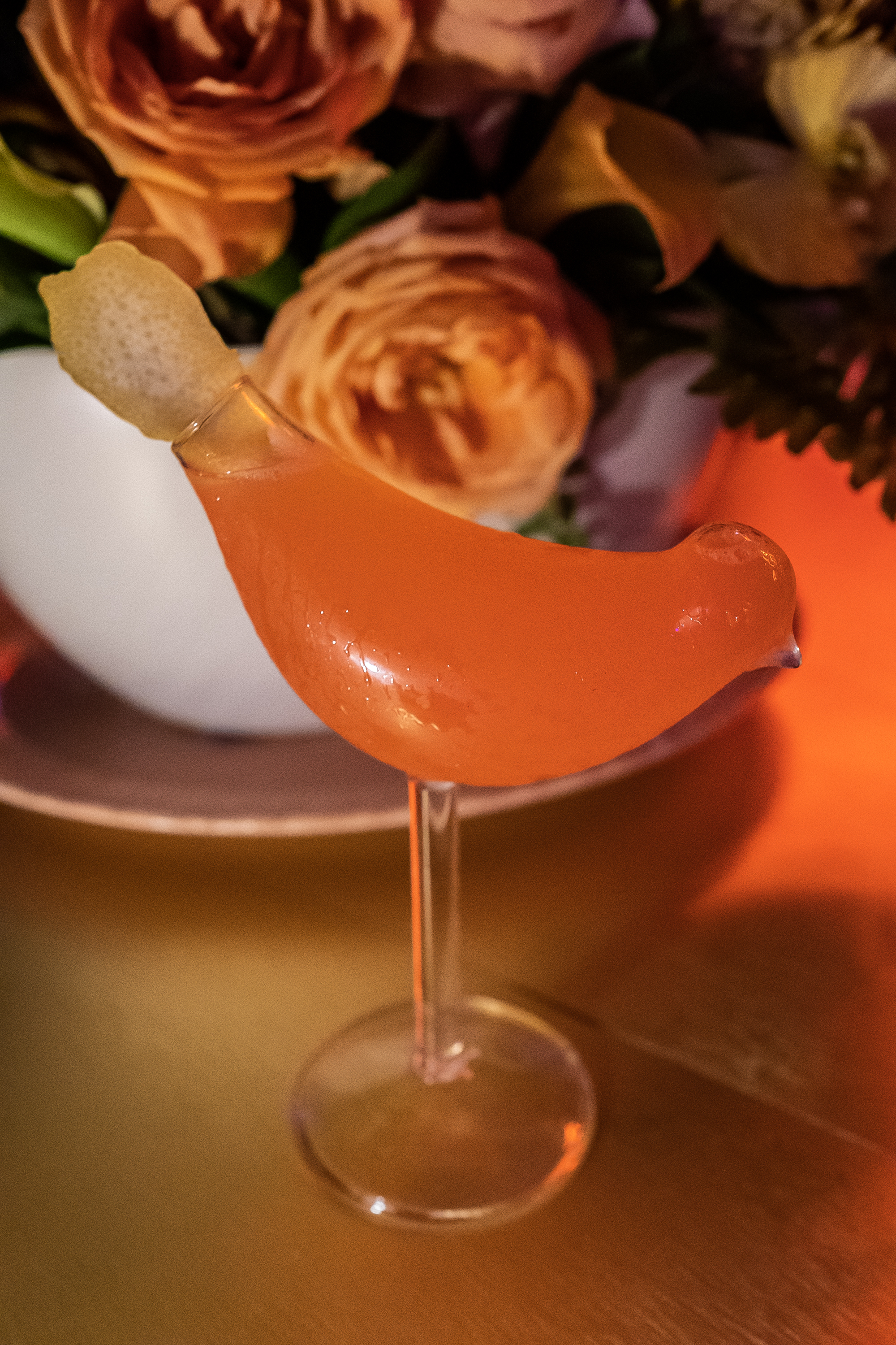 A bird-shaped glass with orange liquid.