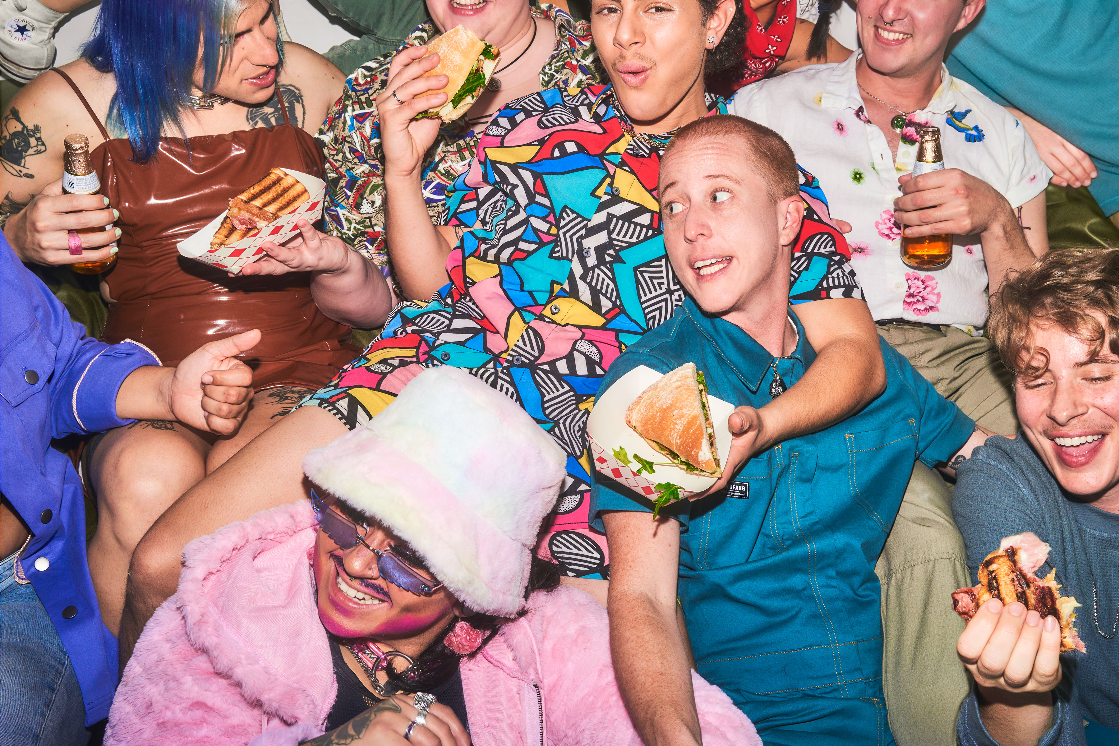 A group of people at a Slutty Sammys pop-up with sandwiches and beer.