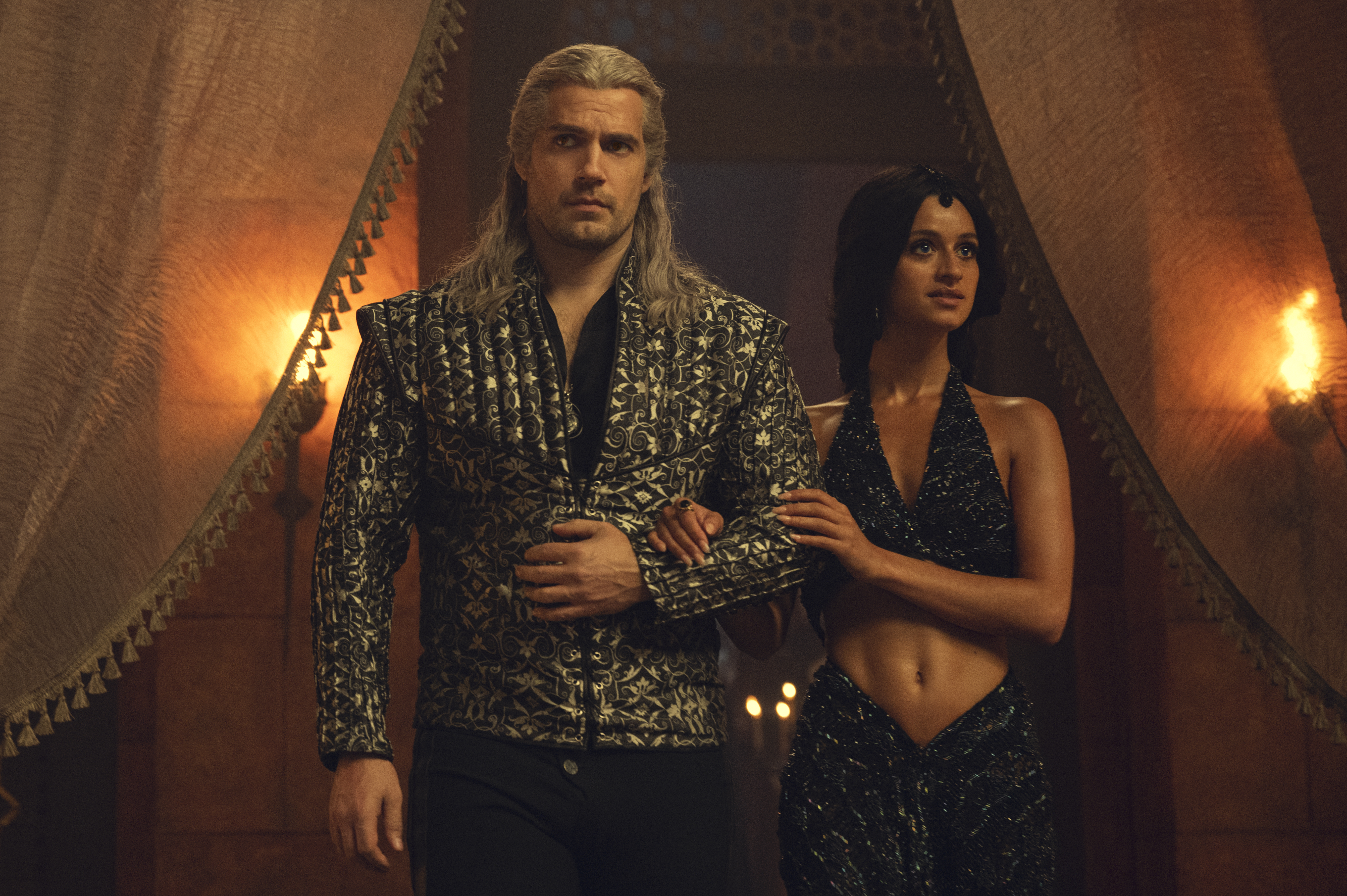 Geralt (Henry Cavill) and Yen (Anya Charlotra) arriving at a party in fancy clothes