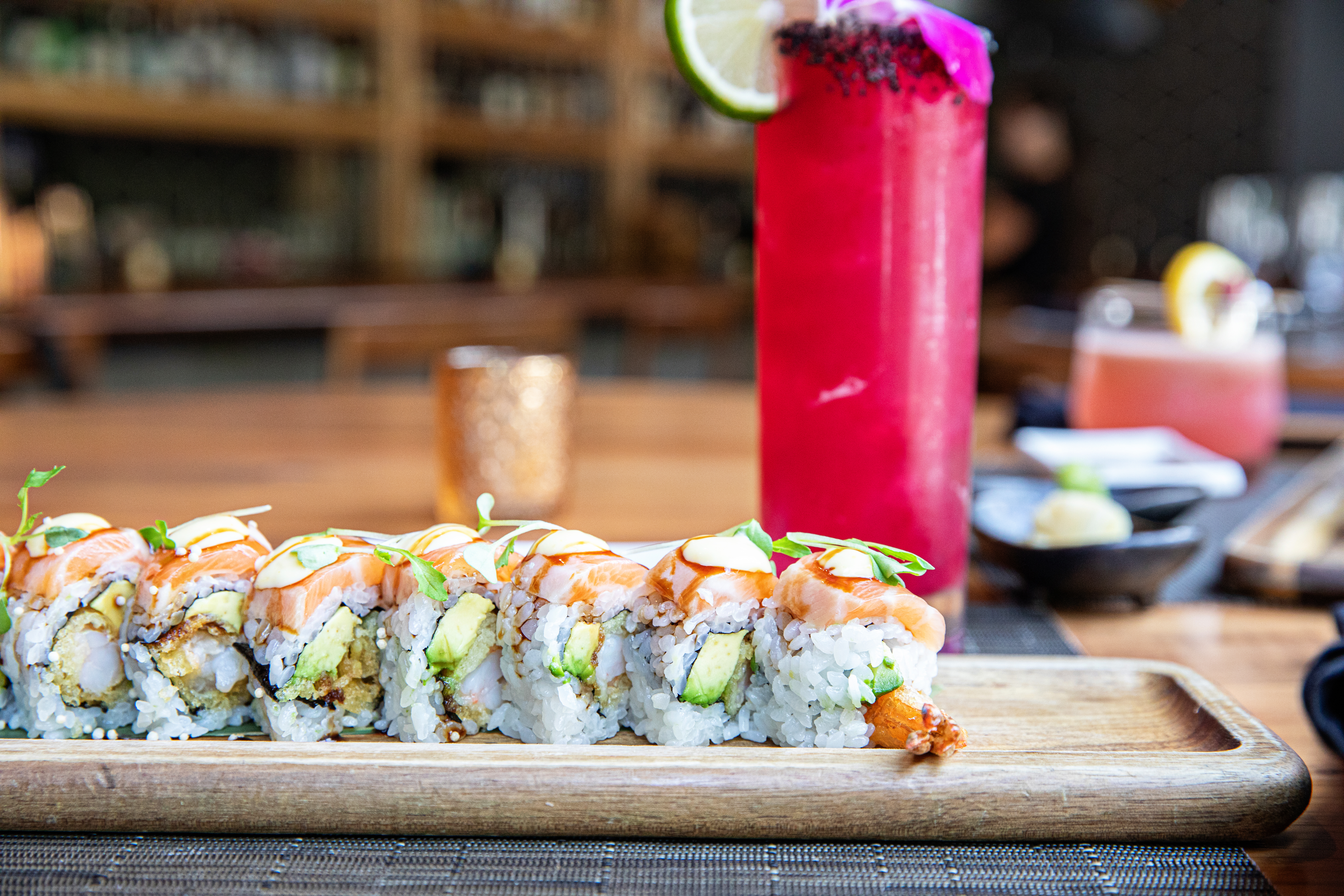 A sushi roll in front of a pink cocktail. 
