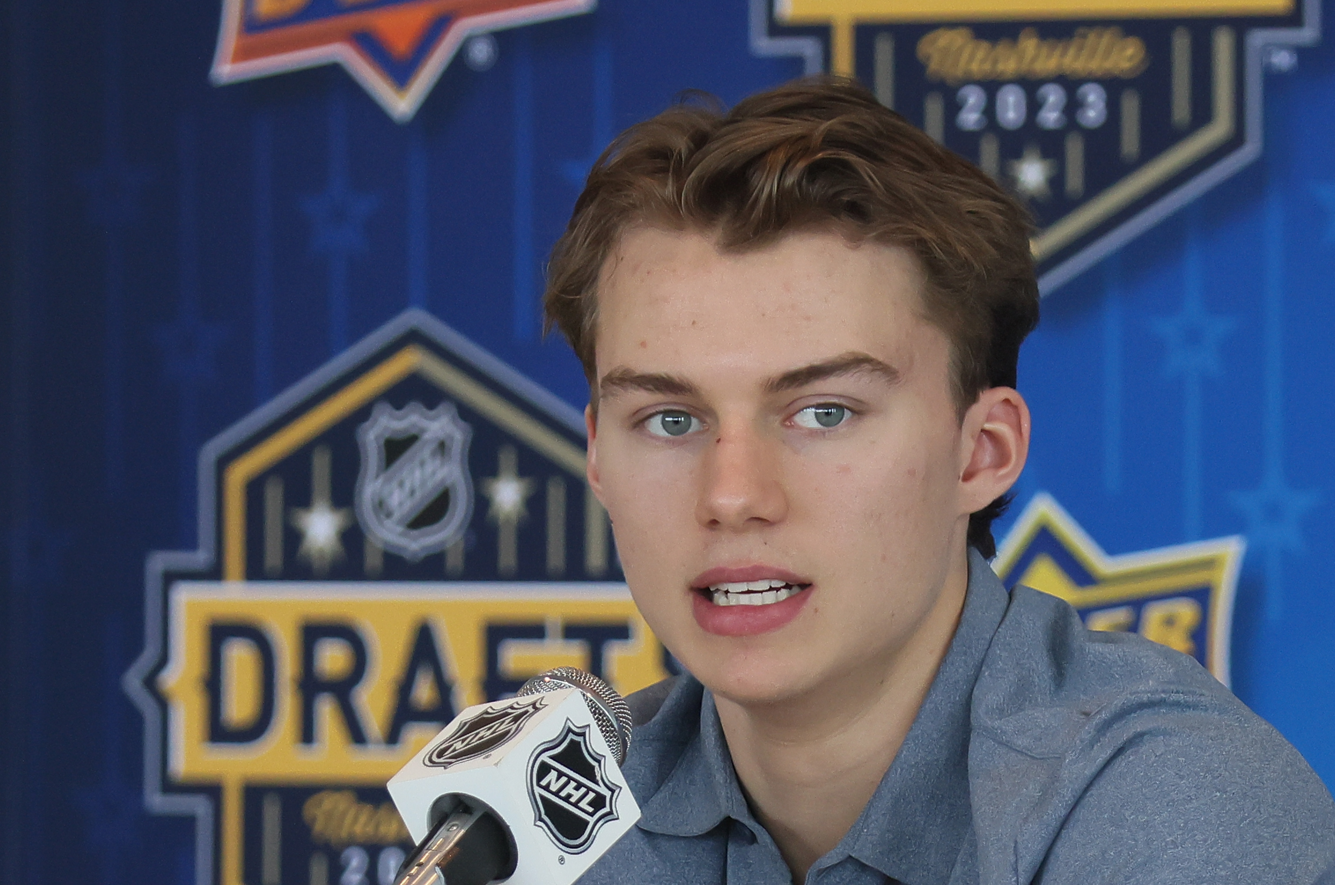 Background:&nbsp;NASHVILLE, TENNESSEE - JUNE 27: NHL prospect Connor Bedard speaks with the media at a press availability at AllianceBernstein Tower on June 27, 2023 in Nashville, Tennessee.