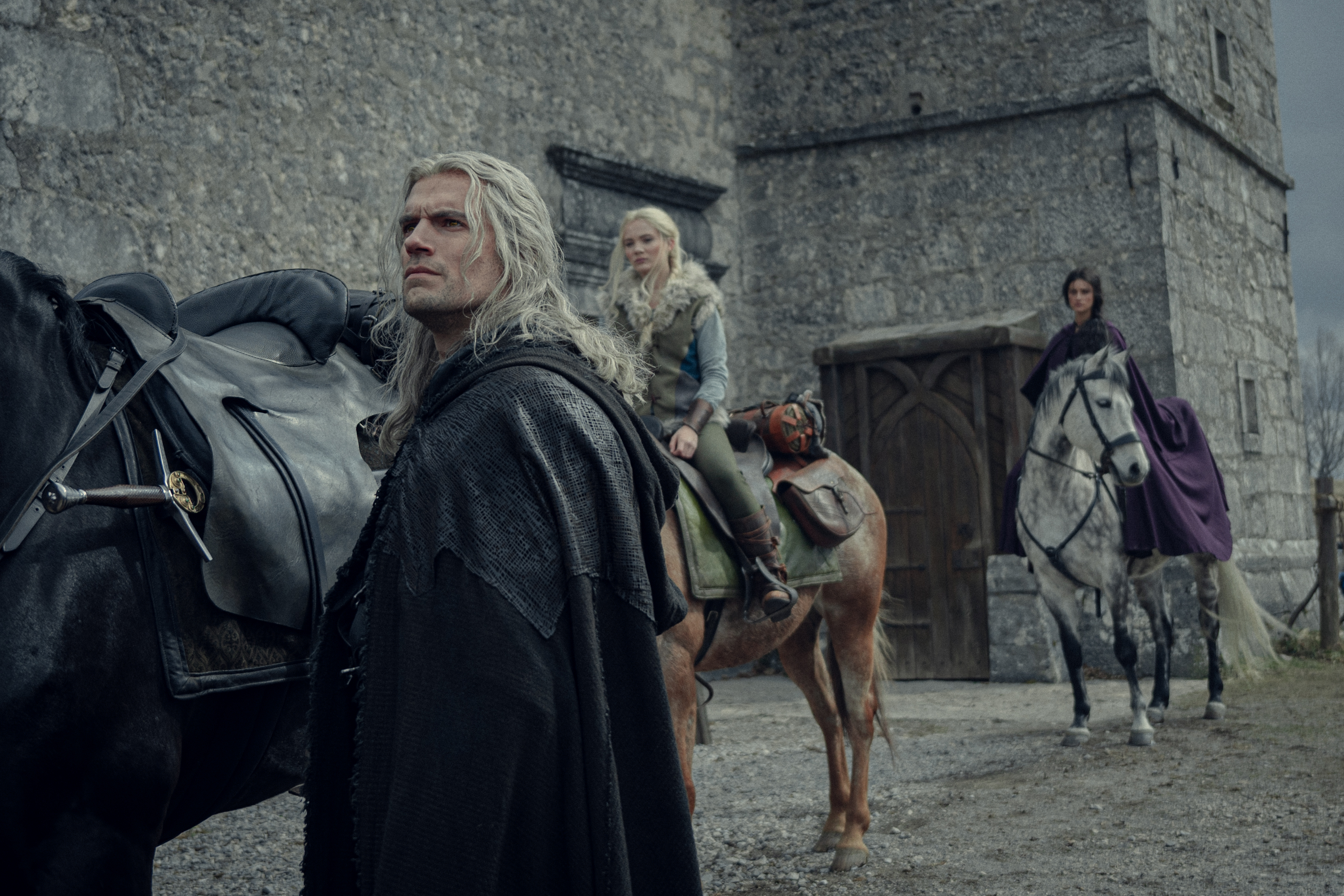 Geralt (Henry Cavill), Ciri (Freya Allan), and Yen (Anya Charlotra) get ready to ride their horses in a still from The Witcher season 3