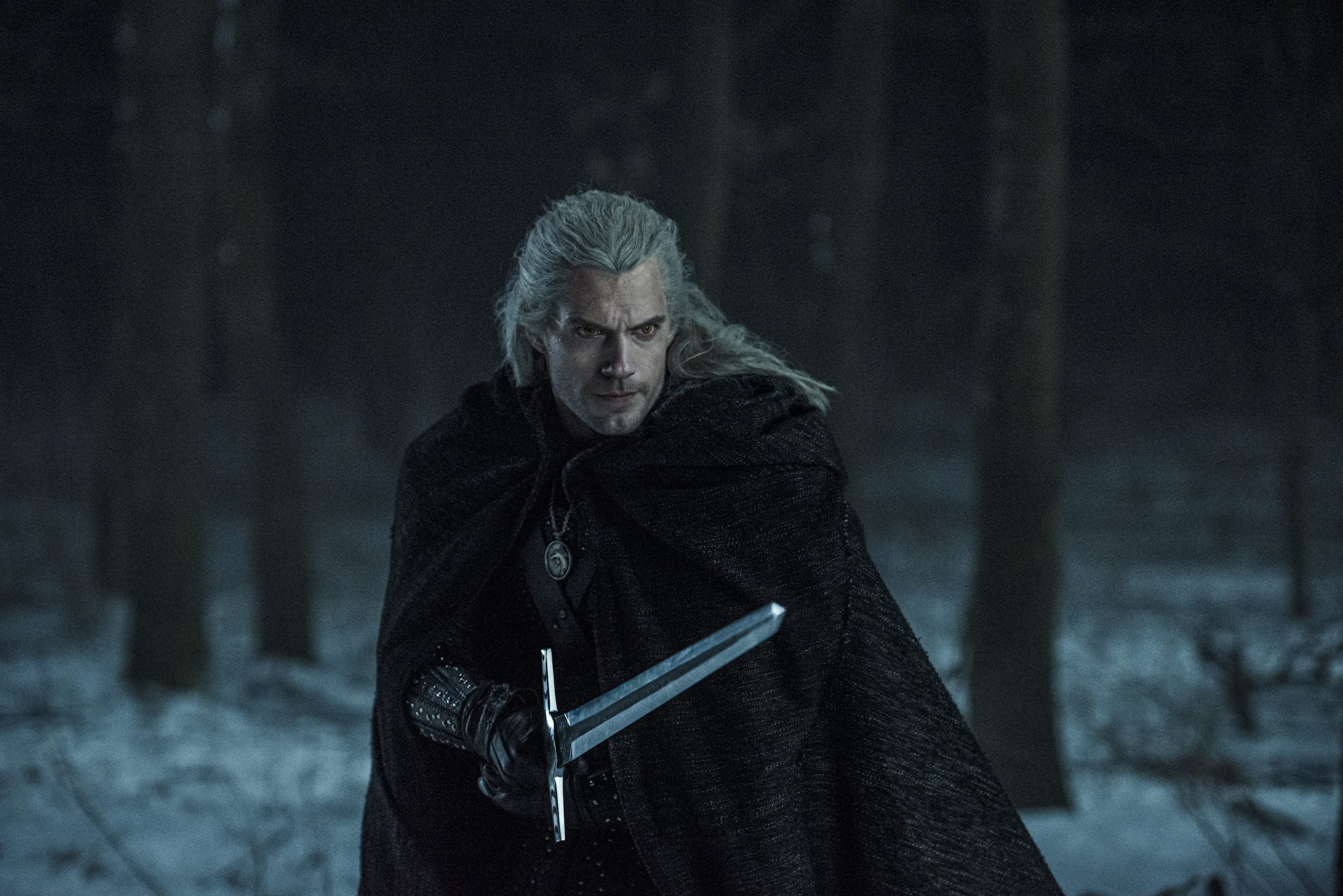 A man with long, white hair wields a sword.