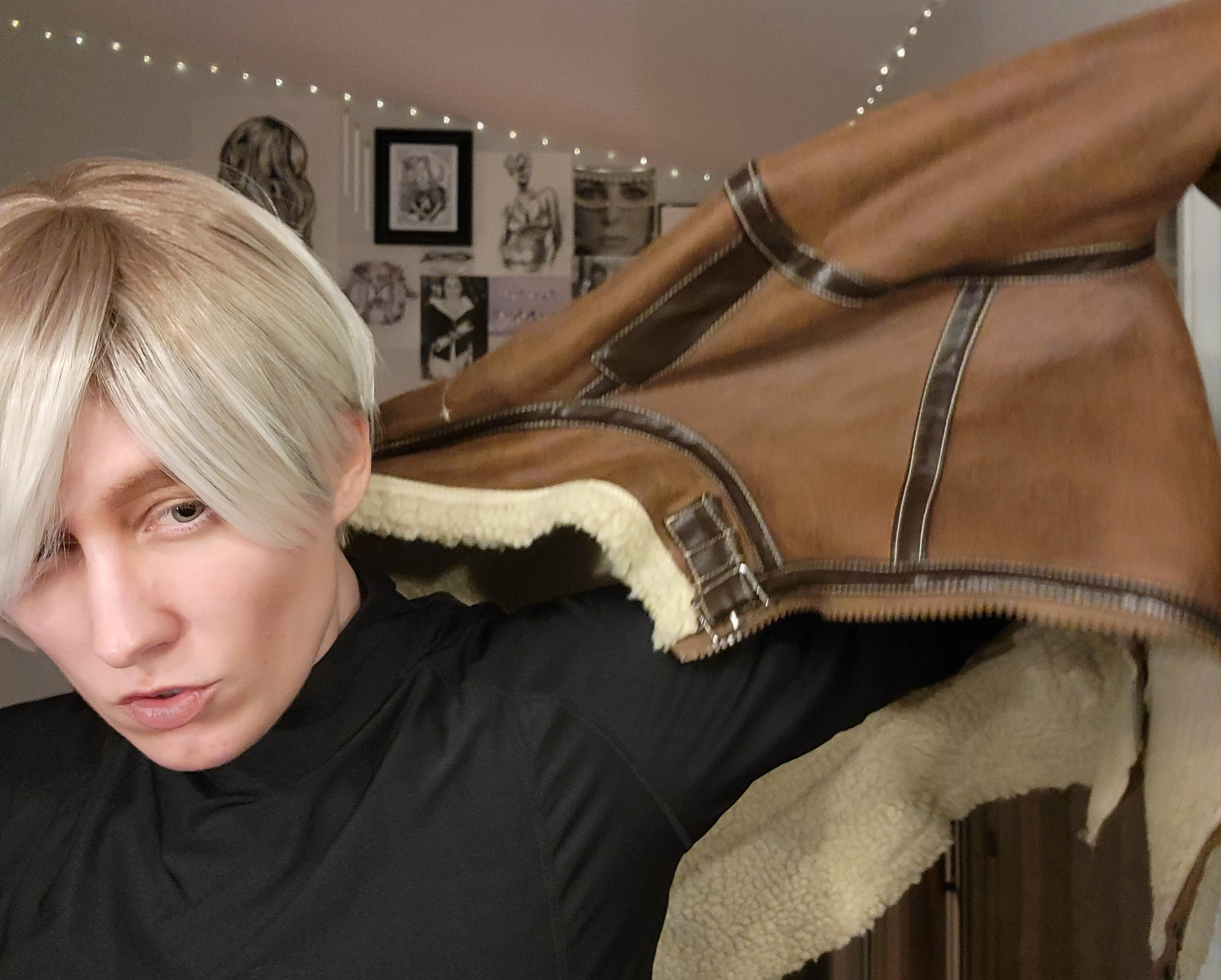 The author in a black turtleneck and blond wig, pulling a brown jacket over her shoulders to complete the Leon Kennedy look
