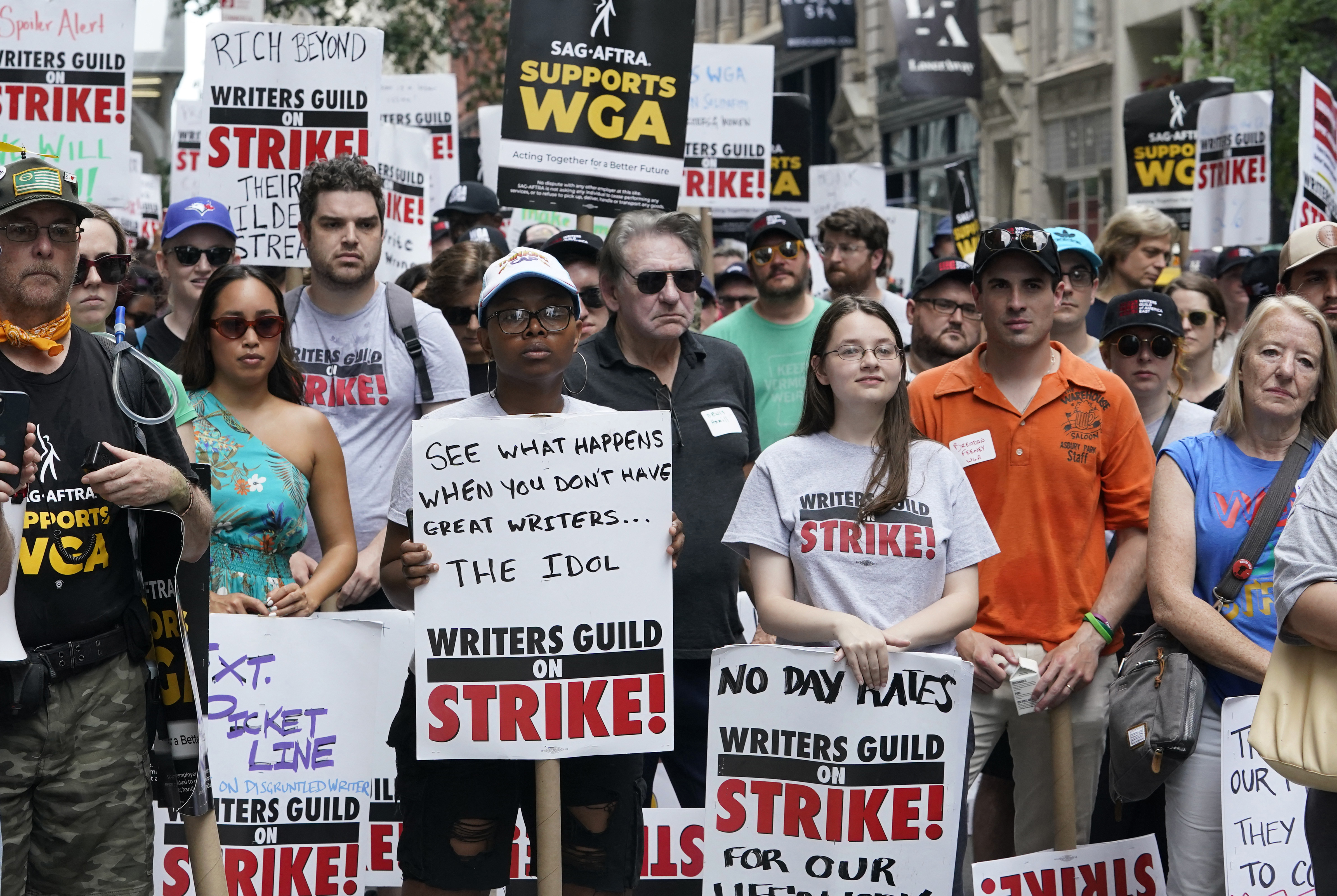 A crowd of people holding signs reading Writers Guild Strike. 