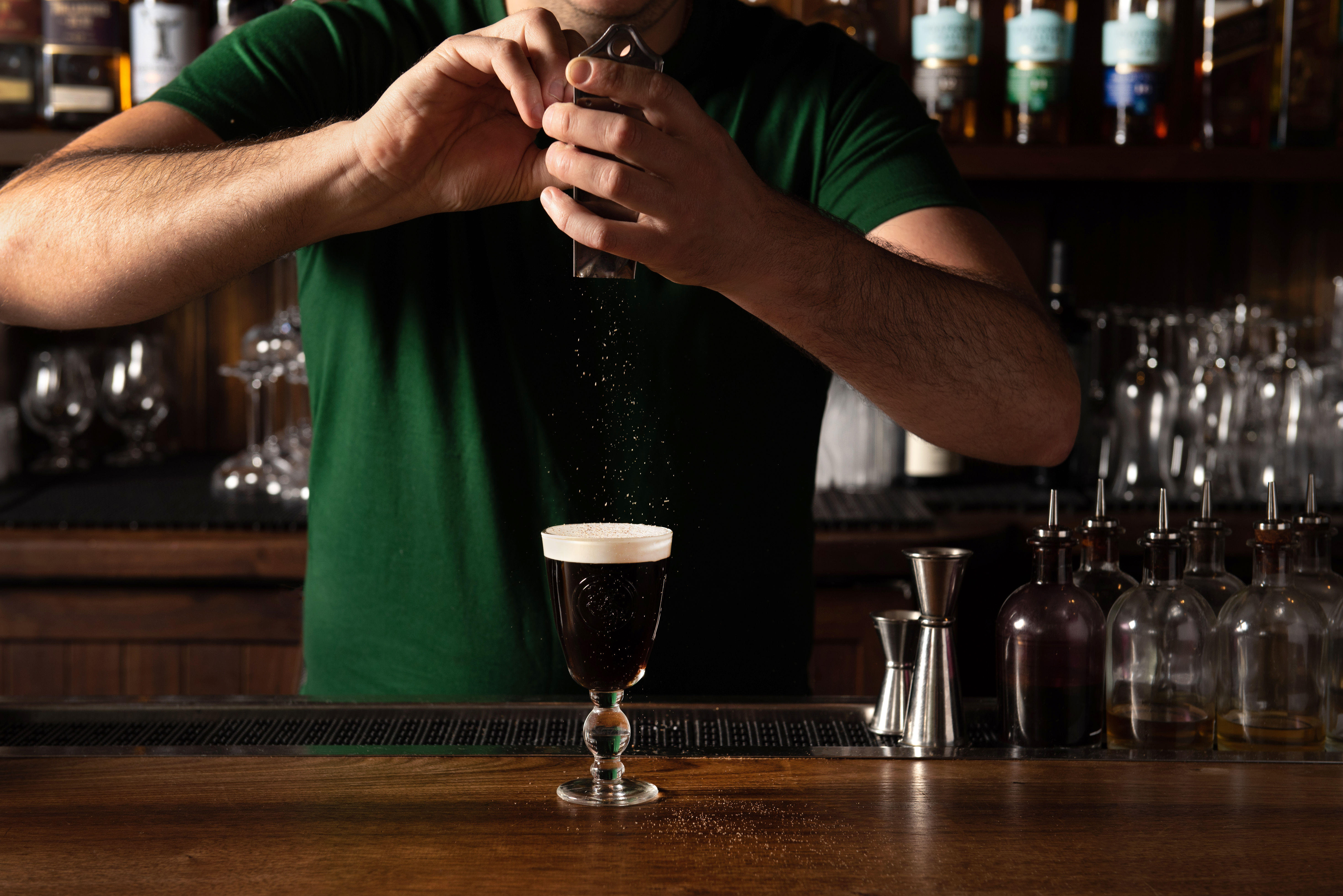 A bartender adds a garnish to a cocktail, the Irish coffee from the cocktail bar the Dead Rabbit.