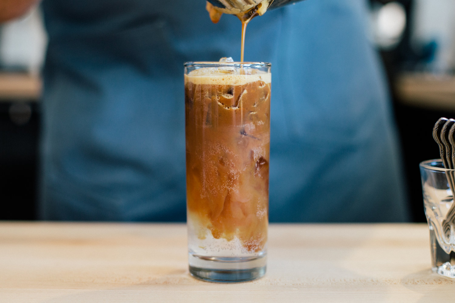 An iced coffee drink in a tall clear glass.