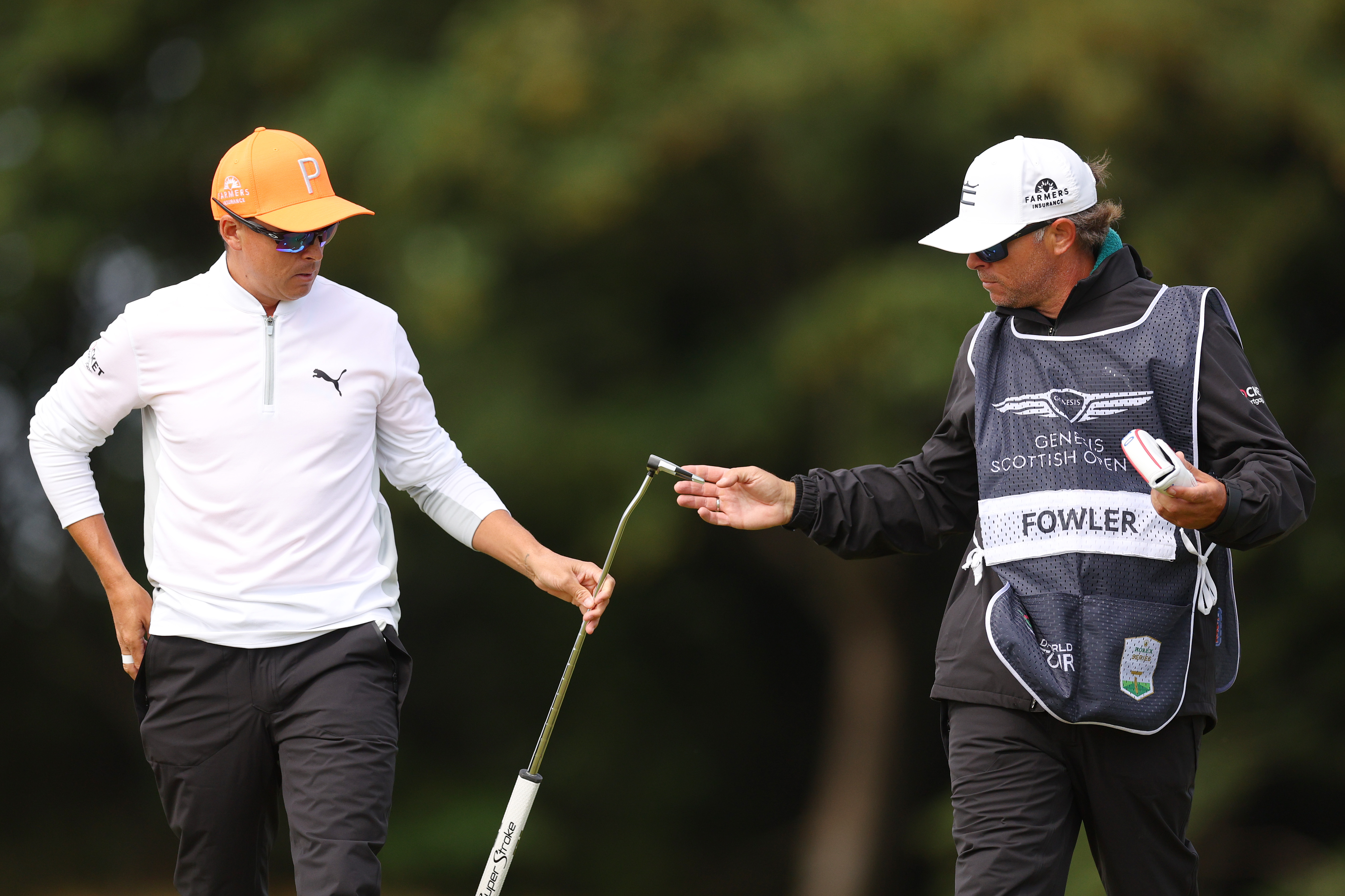 Rickie Fowler of the United States passes his putter to his caddie Ricky Romano on the 10th hole during Day Four of the Genesis Scottish Open at The Renaissance Club on July 16, 2023 in United Kingdom.
