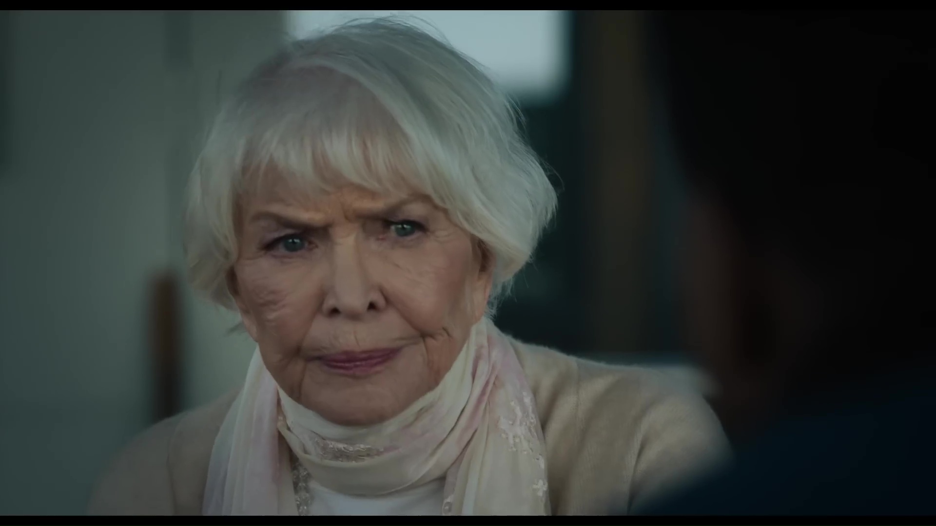 Ellen Burstyn in The Exorcist: Believer wearing a white sweater and looking at someone across a table