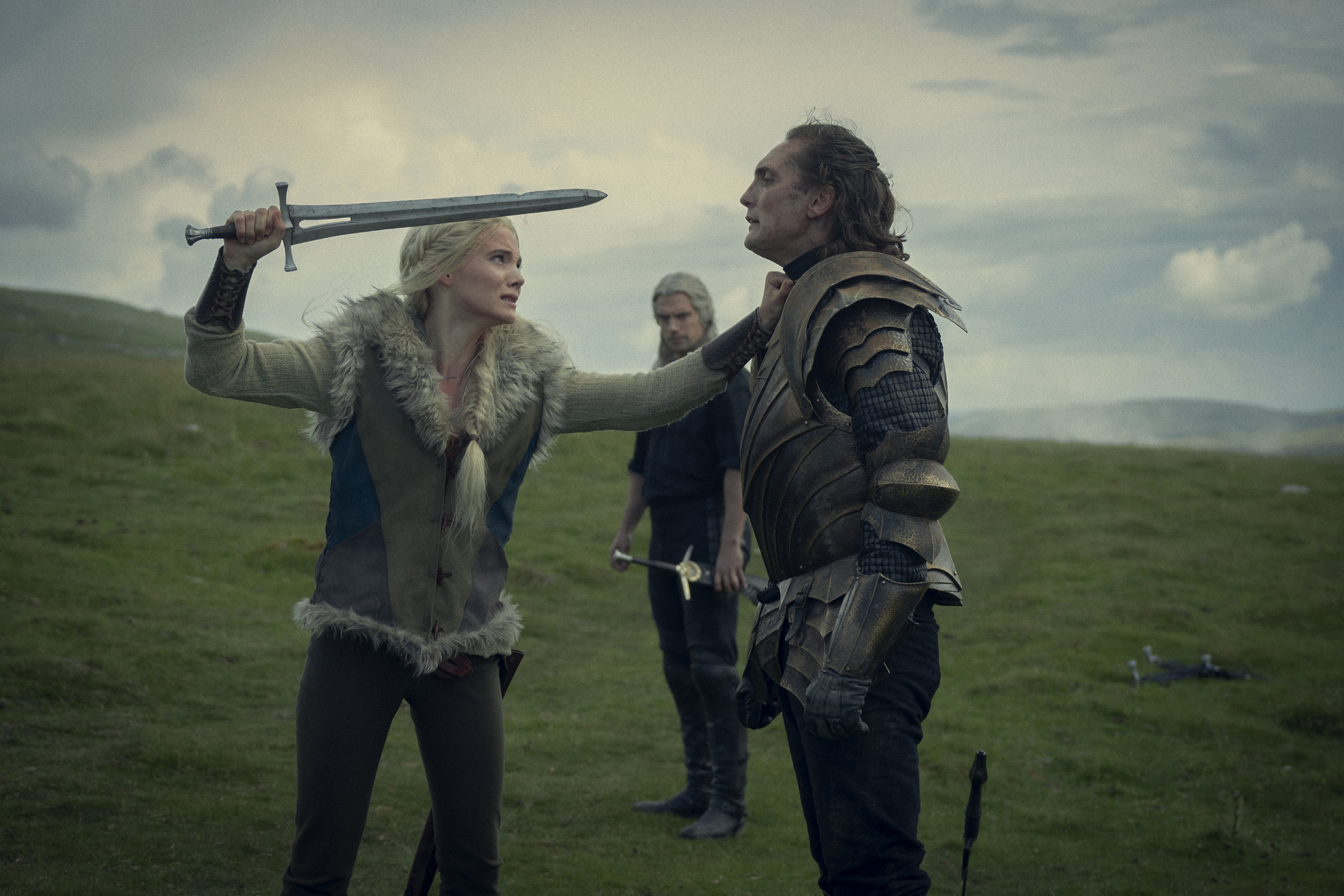 Ciri (Freya Allan) holding a sword up to Cahir (Eamon Farren) and holding him by the throat, while Geralt (Henry Cavill) looks on in the background