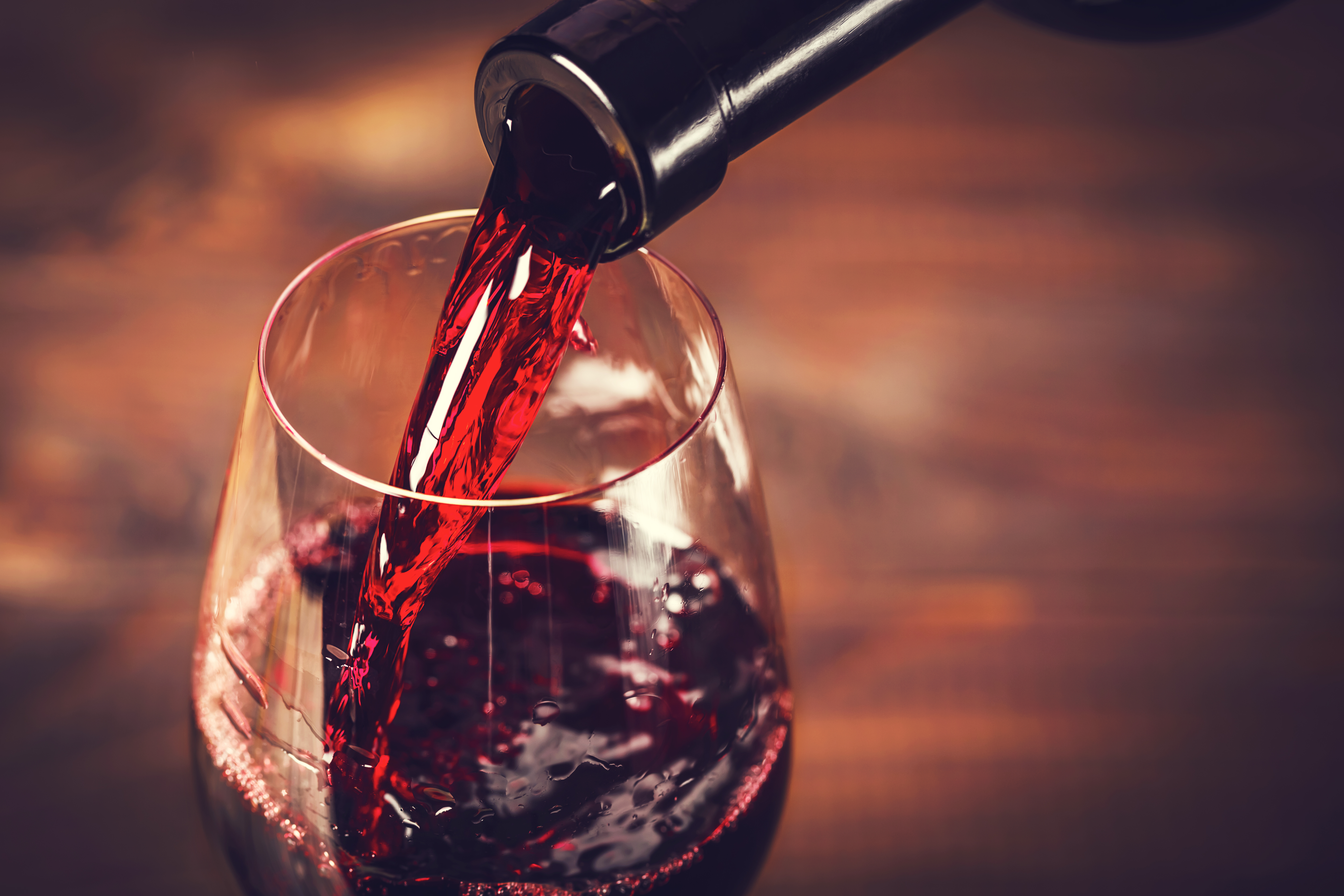 A bottle pouring red wine into a glass