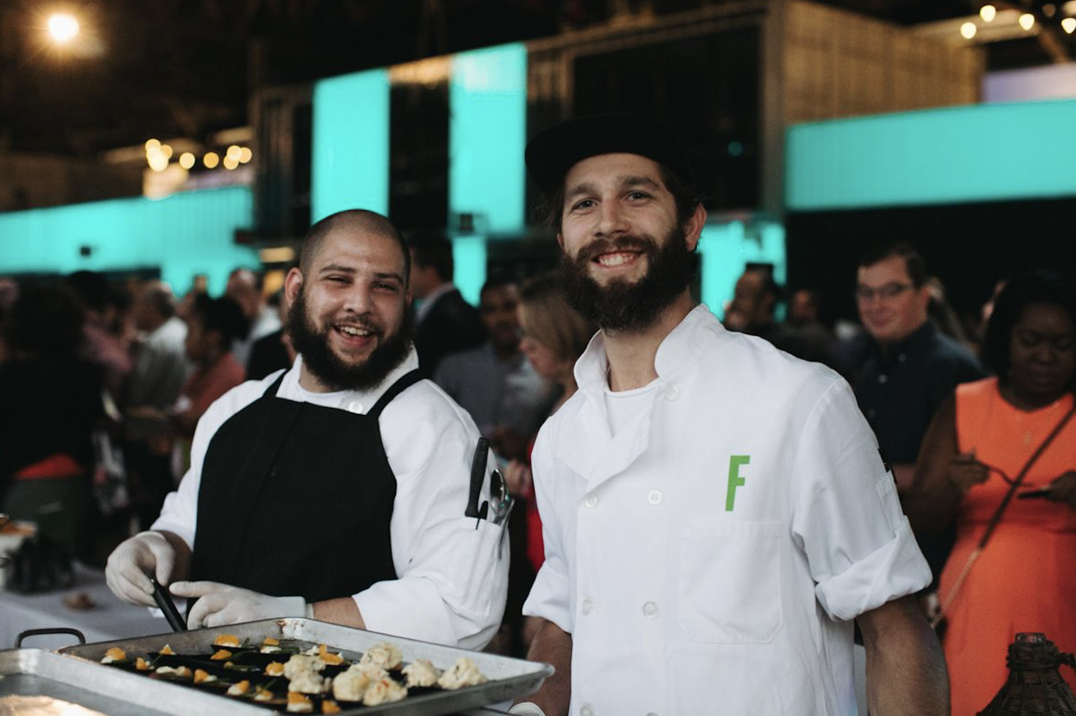 Two chefs standing next to each other serving dumplings at Feastival.