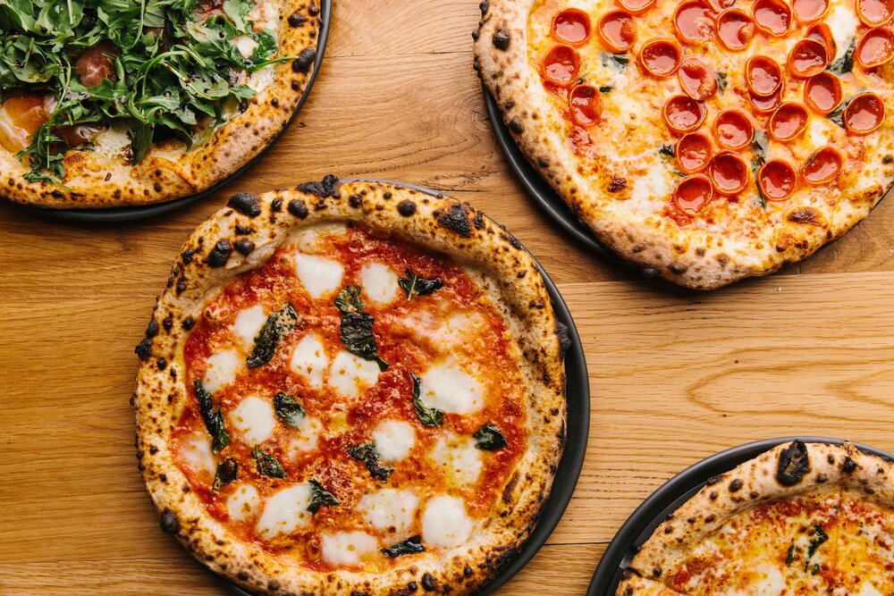An overhead shot of a whole arugula&nbsp;and prosciutto pizza, pepperoni pizza, margherita pizza, and cheese pizza from Grana in Atlanta. 