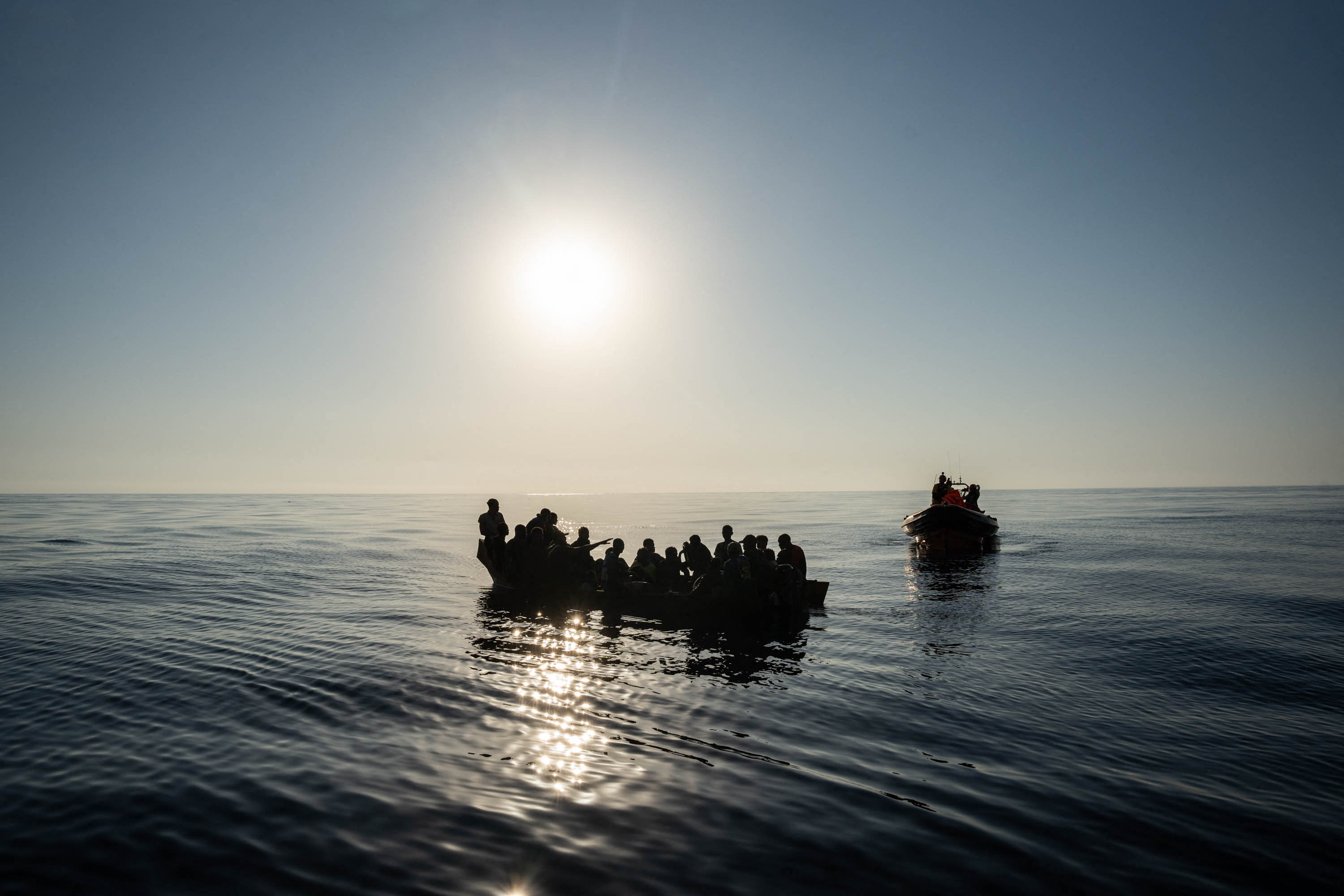 small, overcrowded open-air boats containing migrants at sea.