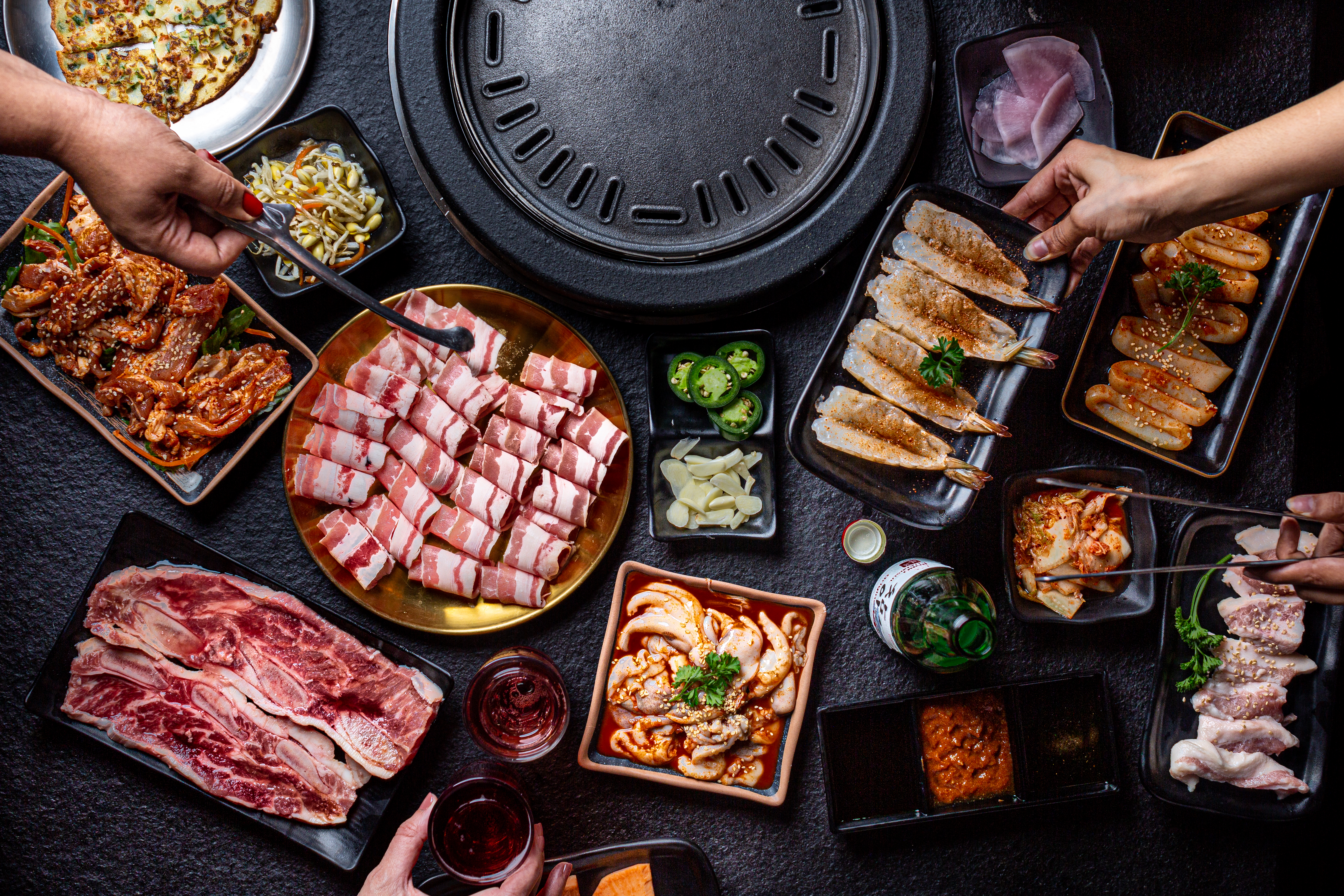 A large spread of grilled meats and banchan.