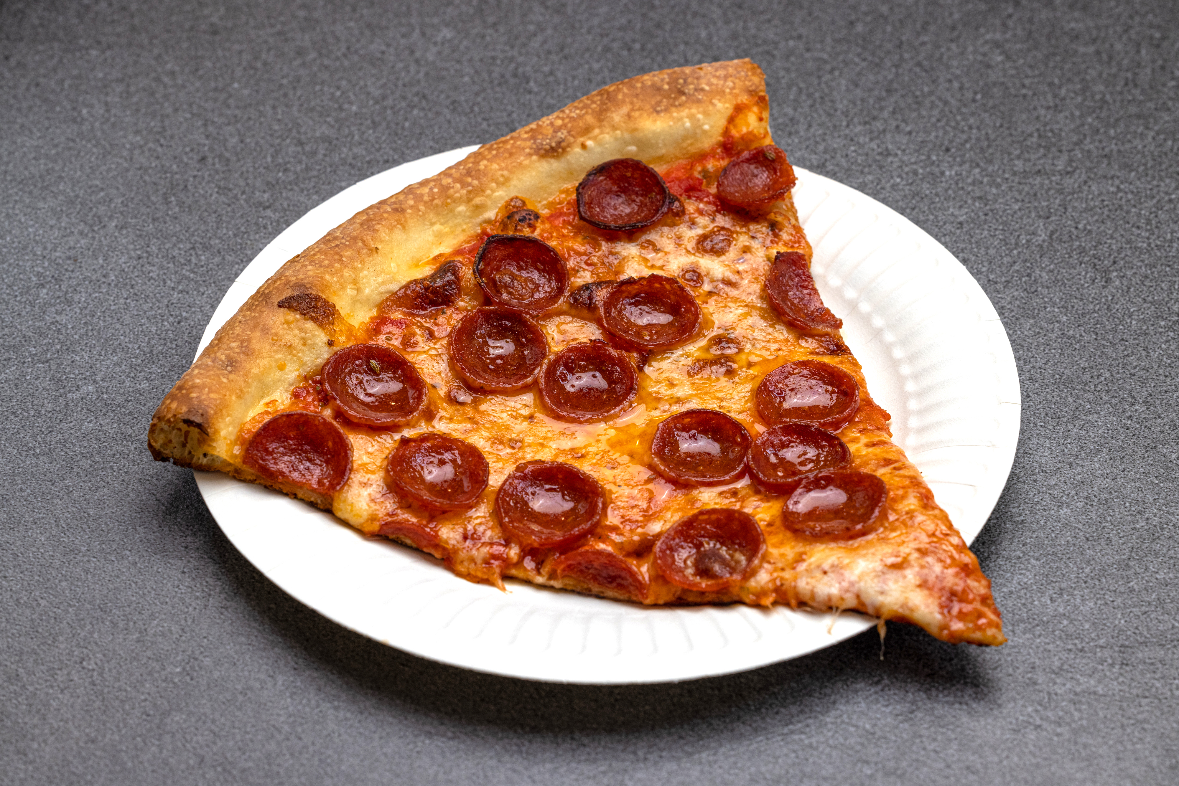 A slice of pepperoni cheese on a paper plate.