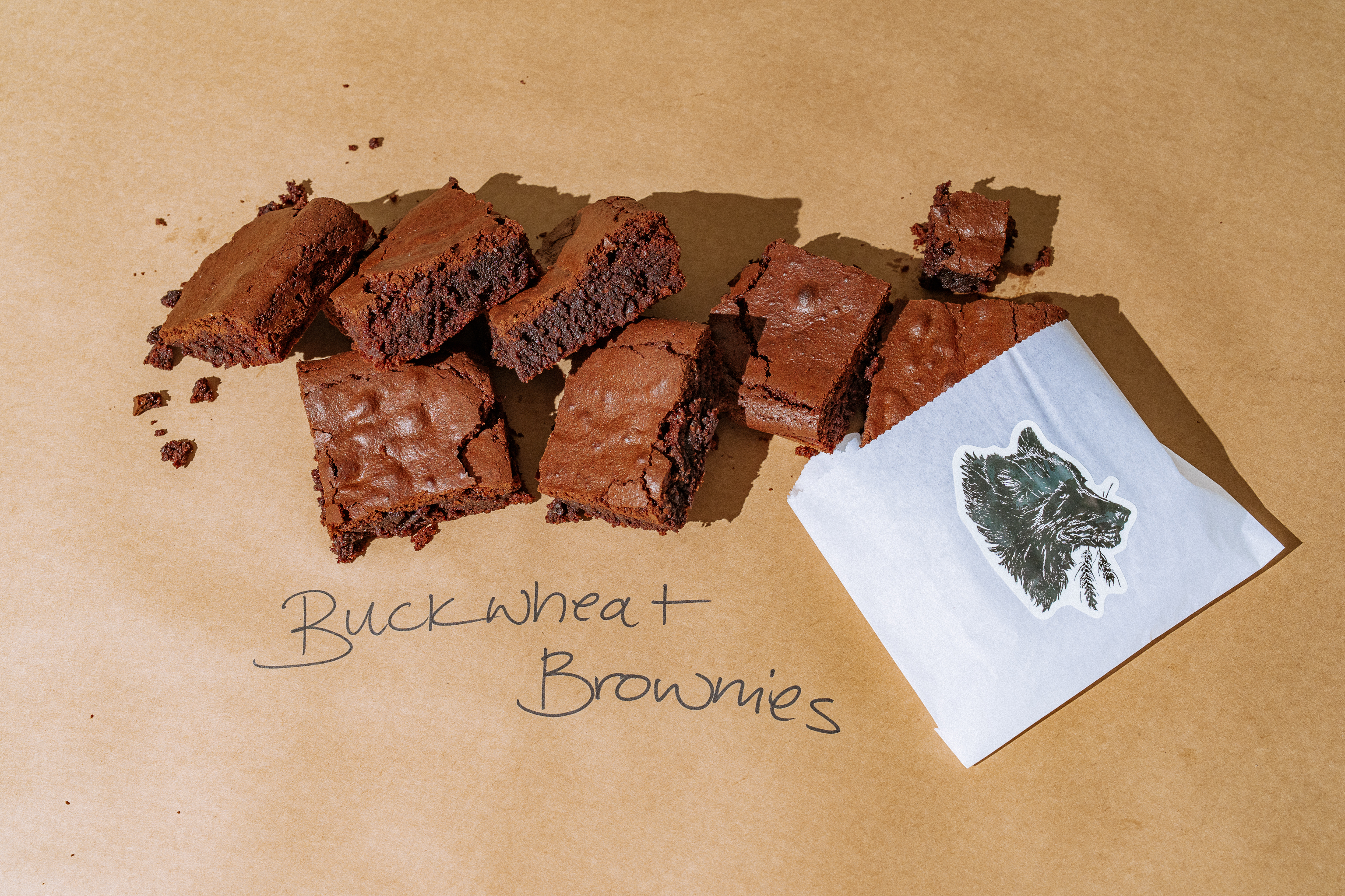 Brownies on butcher paper next to a sticker of a wolf and the words Buckwheat Brownies on the paper.