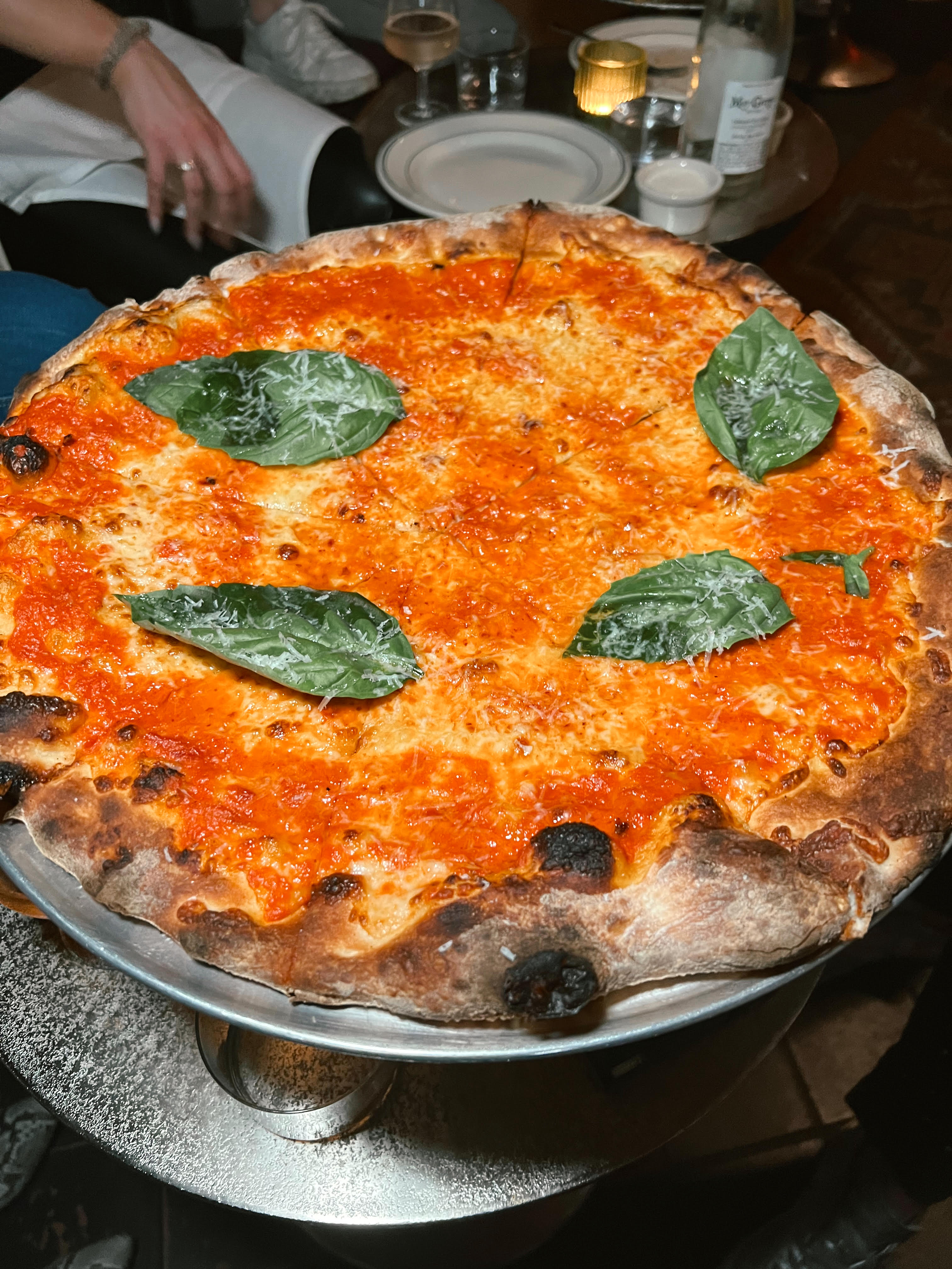 A pizza with reddish-orange sauce and green leaves.