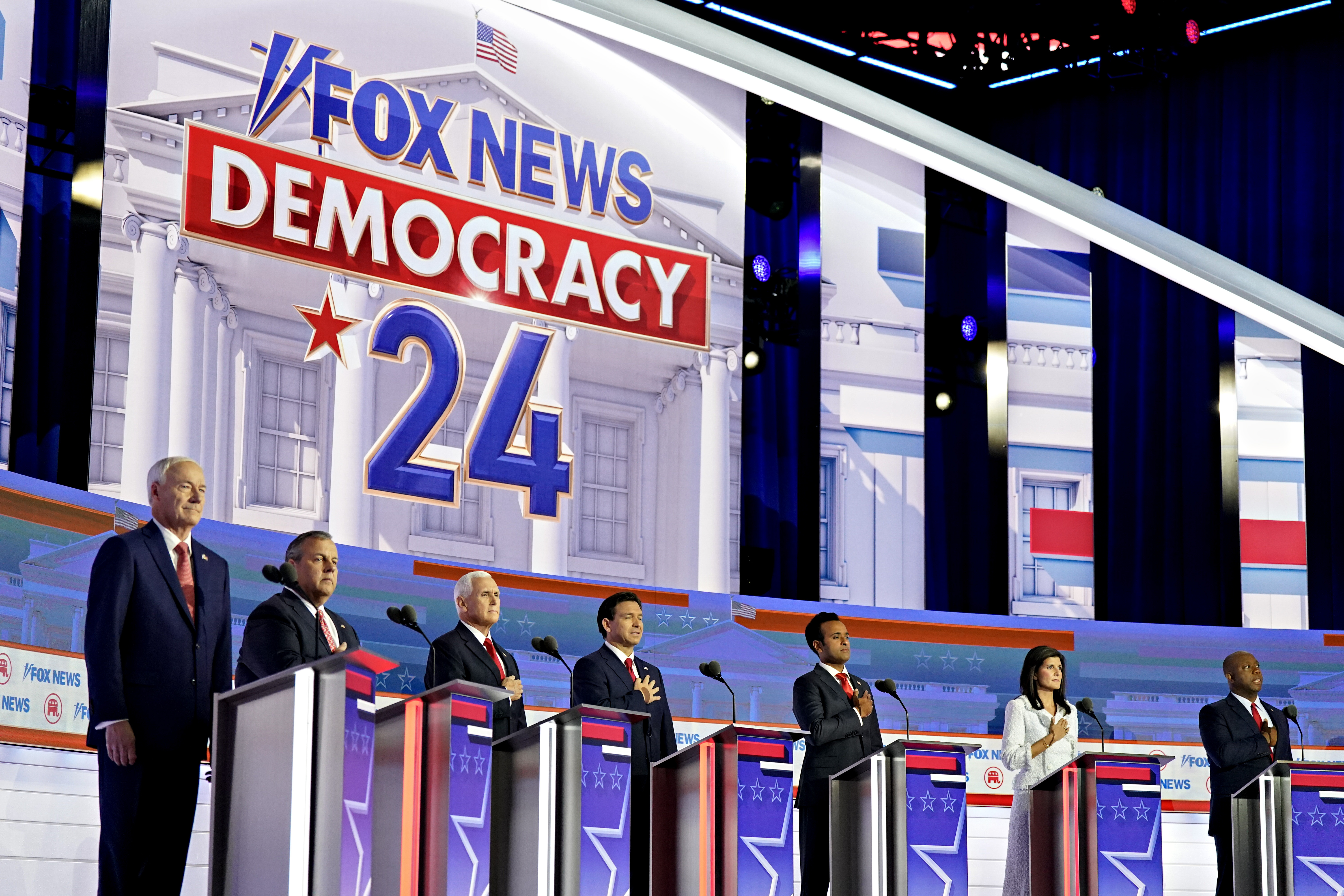 The Republican debate stage with candidates behind podiums in a row.