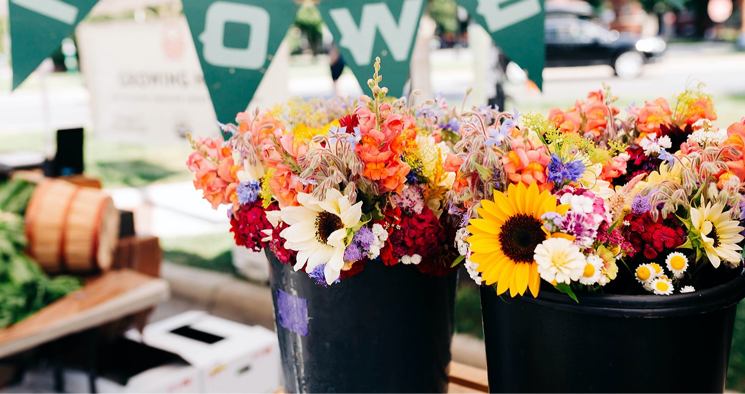 A farmers market display of buckets filled with flowers.